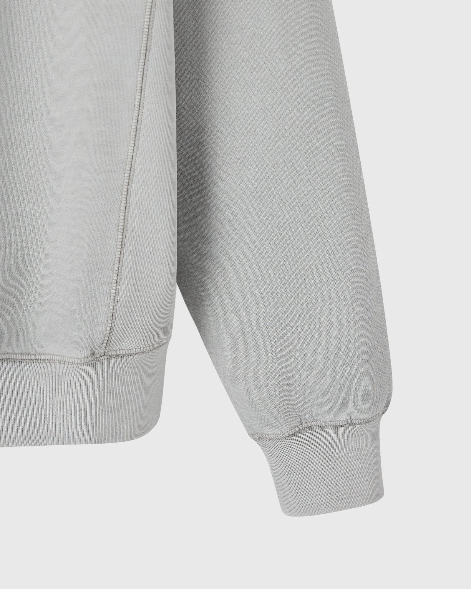 Gray crewneck sweatshirt with ribbed cuffs and hem, shown from side detail view.