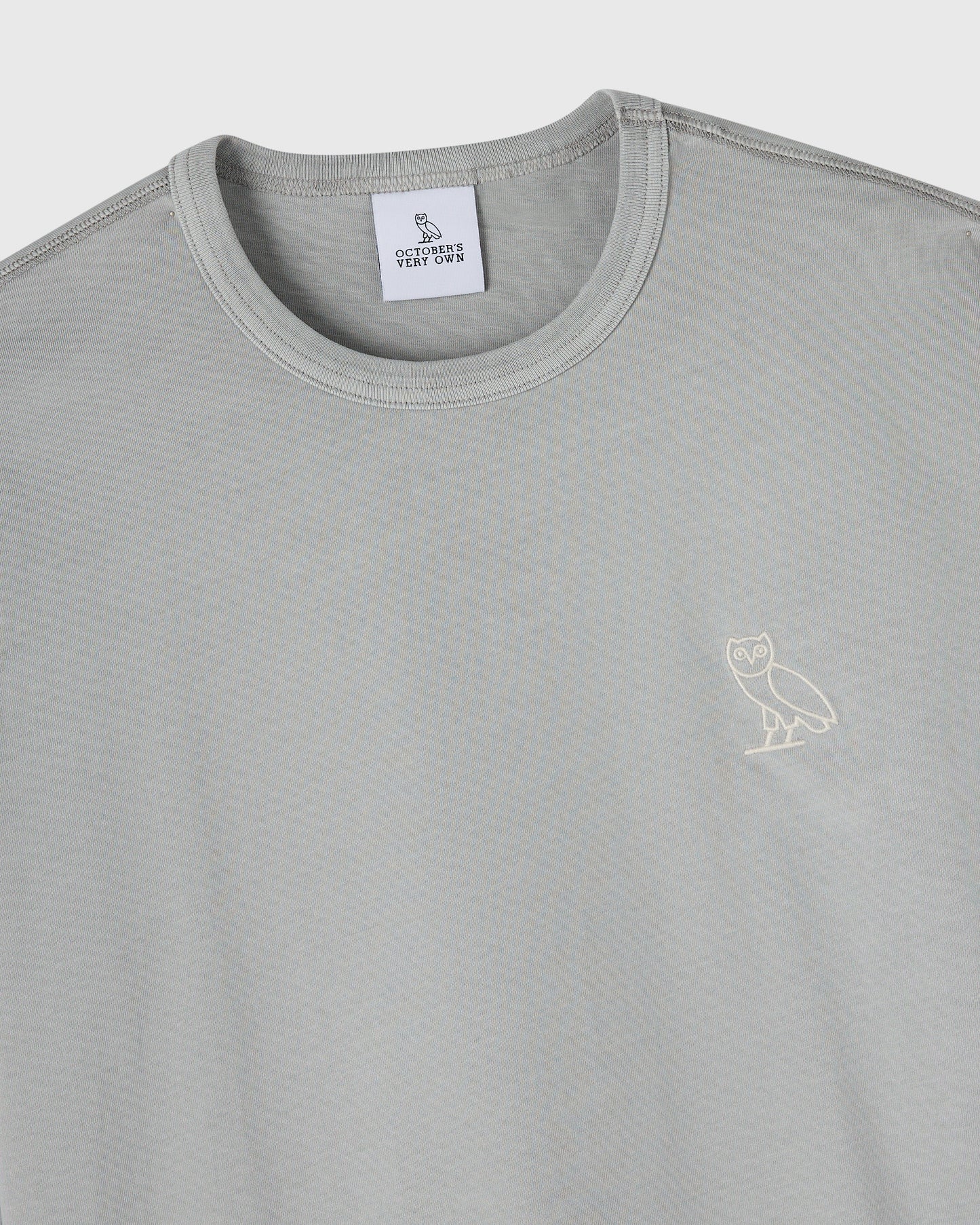 Gray long-sleeve crewneck tee with small owl embroidery on chest and October's Very Own brand label.