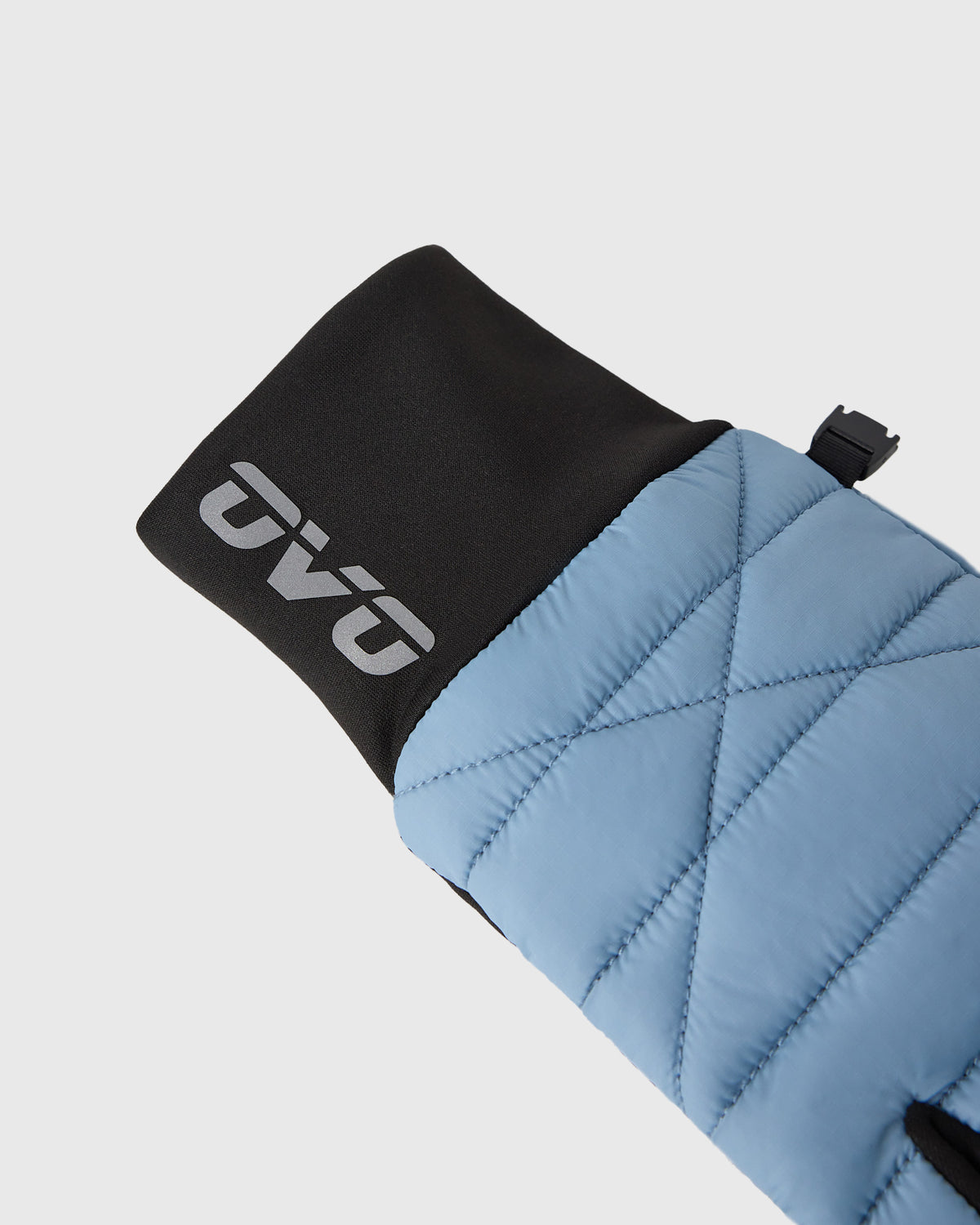 Quilted glove with light blue outer shell, black cuff, and gray logo detail on wrist.