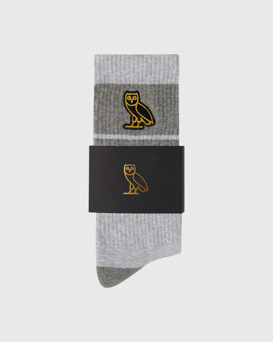 Pair of ash heather grey crew socks with gold owl embroidery and darker grey heel and toe.