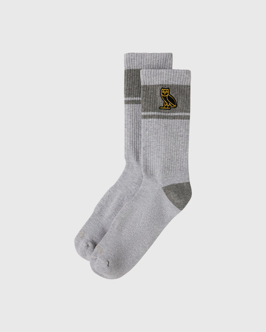 Pair of ash heather grey crew socks with dark grey stripes and owl emblem on cuff.