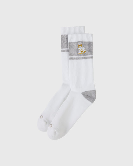 White crew socks with gray stripes, gray heel and toe, and gold owl logo on cuff.