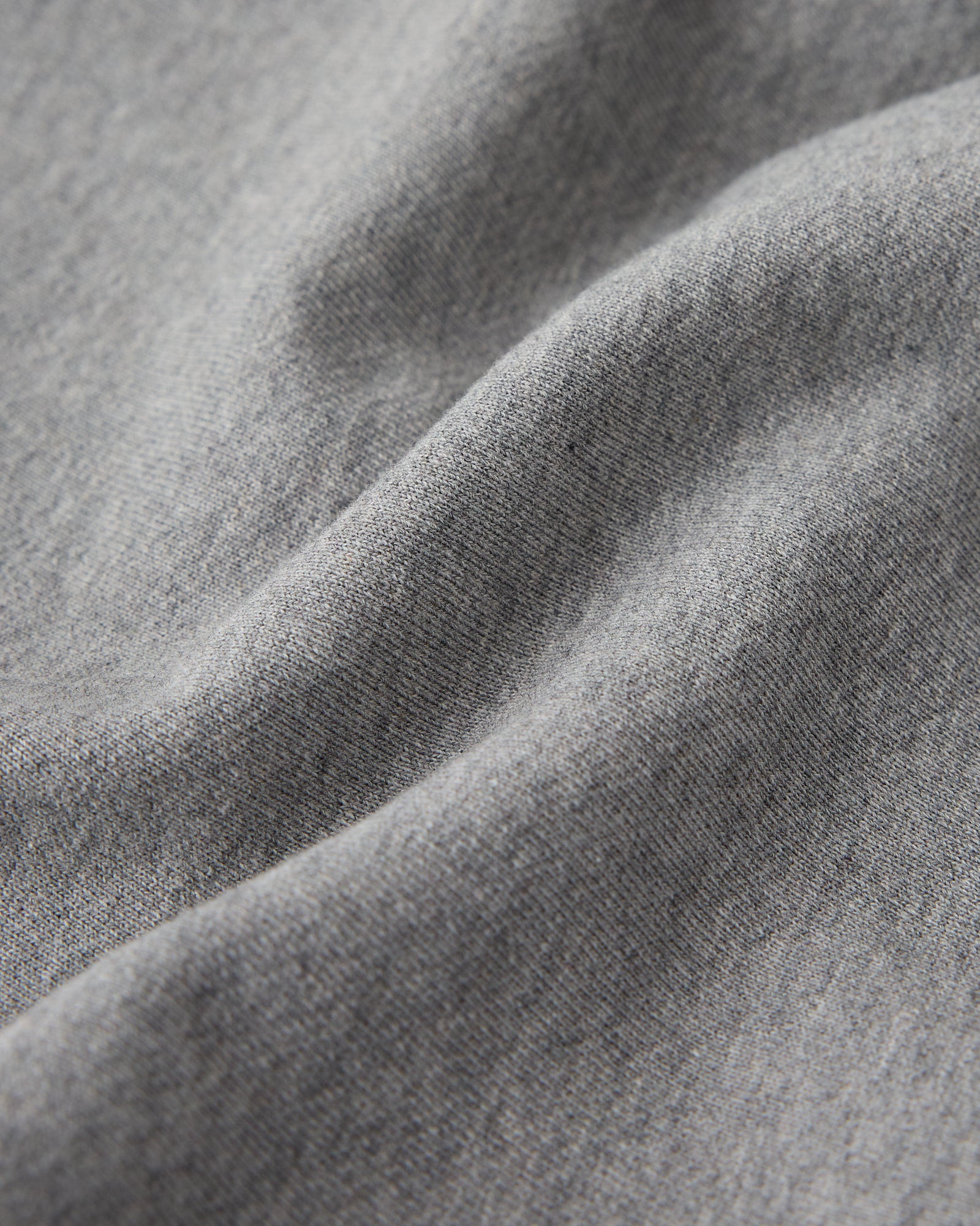 Heather grey sweatshirt fabric with ribbed texture and natural folds showing the material's drape.