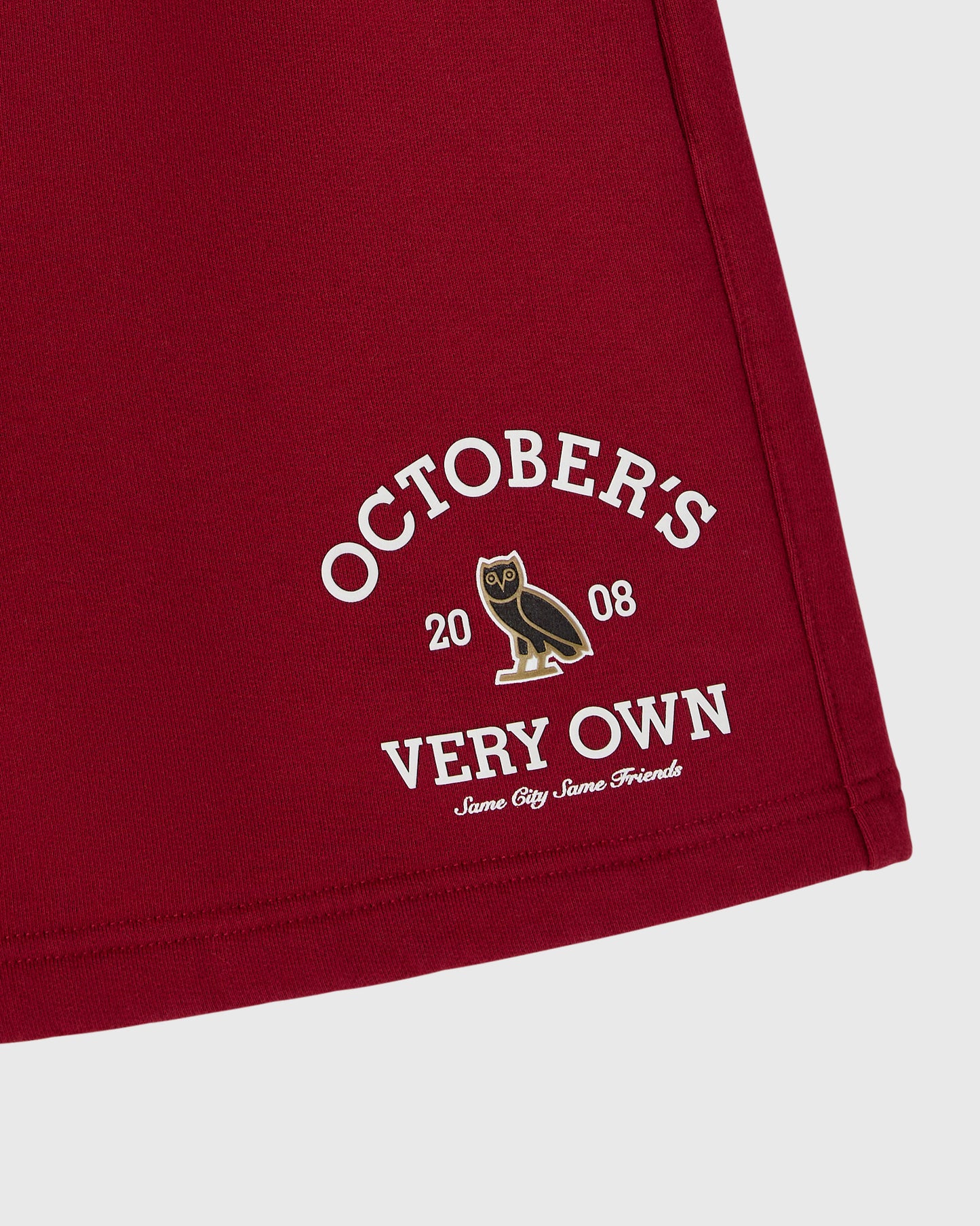 Deep red shorts with "October's Very Own" graphic and owl emblem printed on thigh.