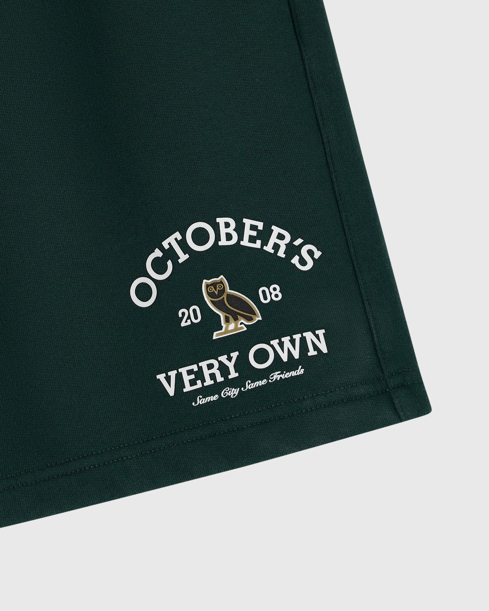 Midnight green shorts with white text reading "October's Very Own" and a gold owl graphic with "2008" printed on the leg.