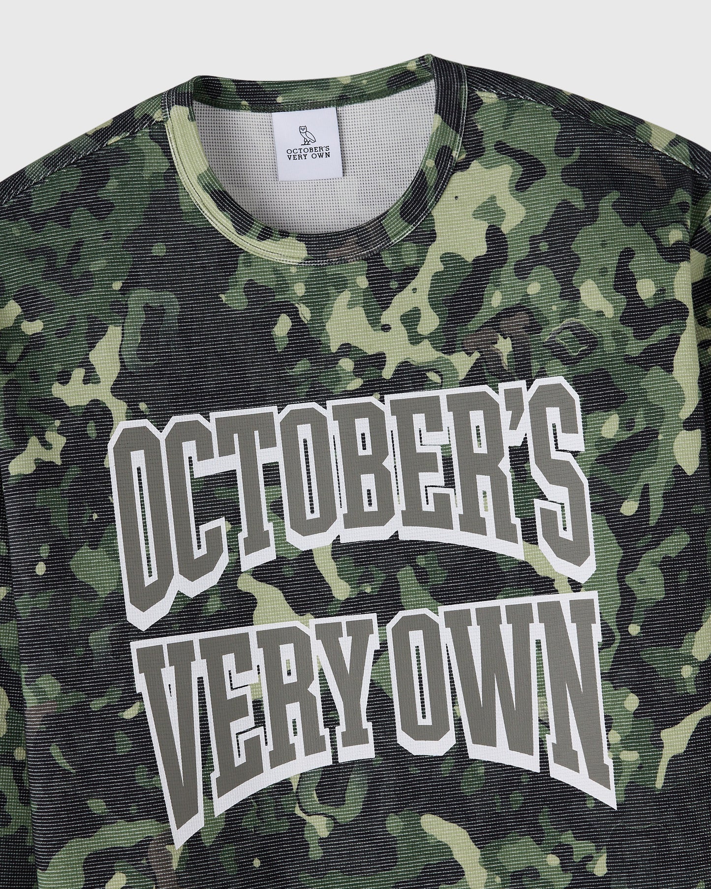 Long-sleeve tee in green and black camouflage pattern with white "October's Very Own" graphic text on chest.