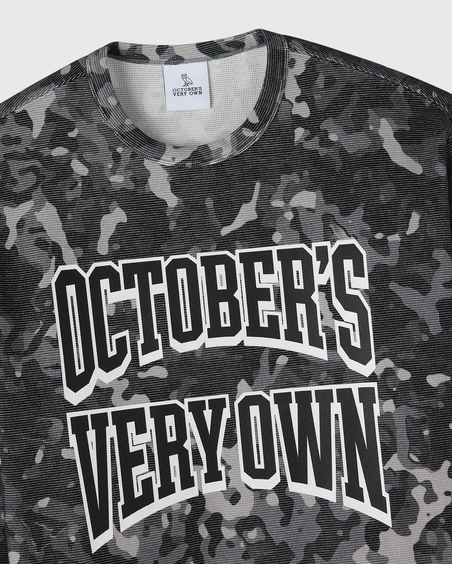 Grey camouflage long-sleeve tee with white "October's Very Own" text graphic on chest.