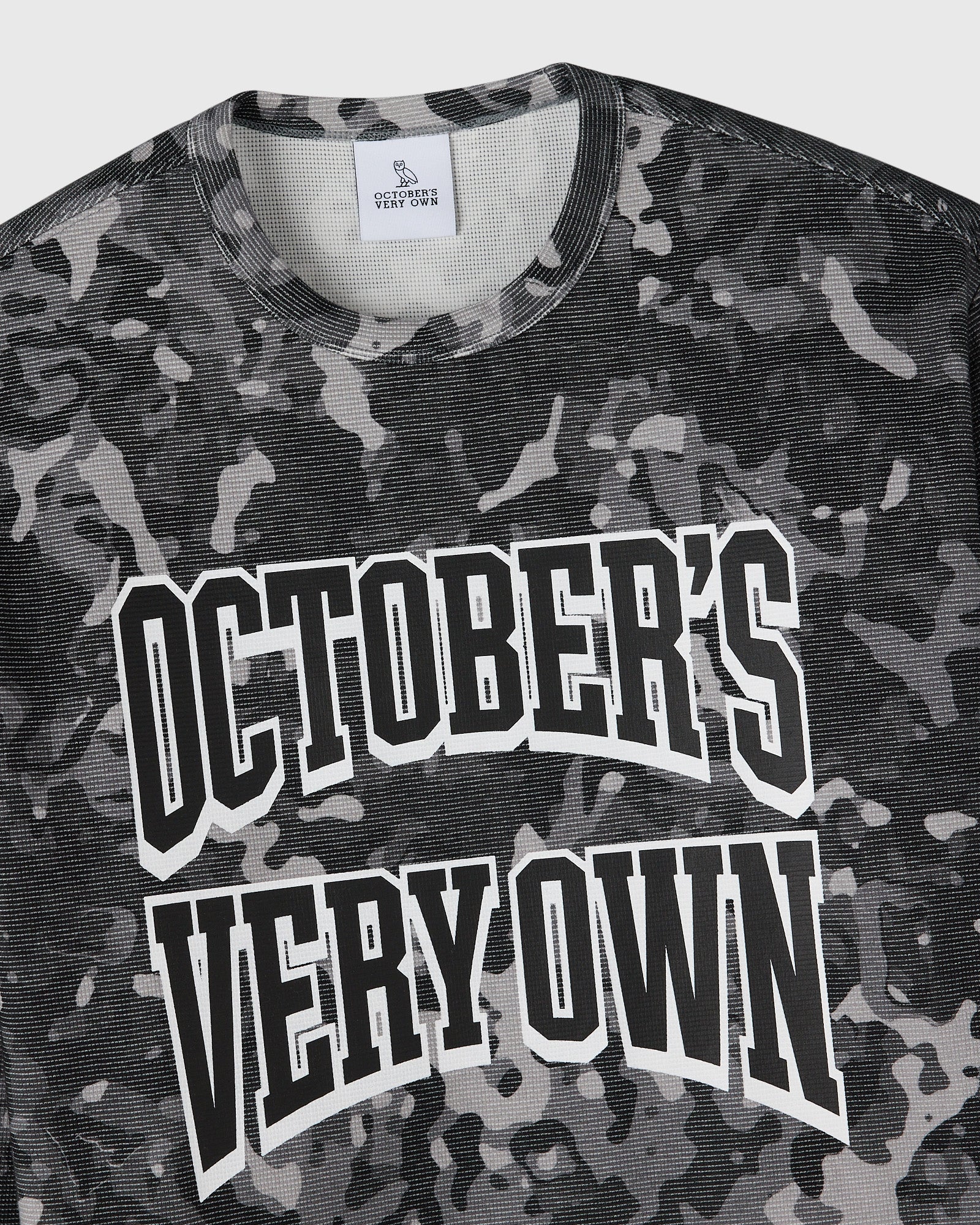 Grey camouflage long-sleeve tee with white "October's Very Own" text graphic on chest.