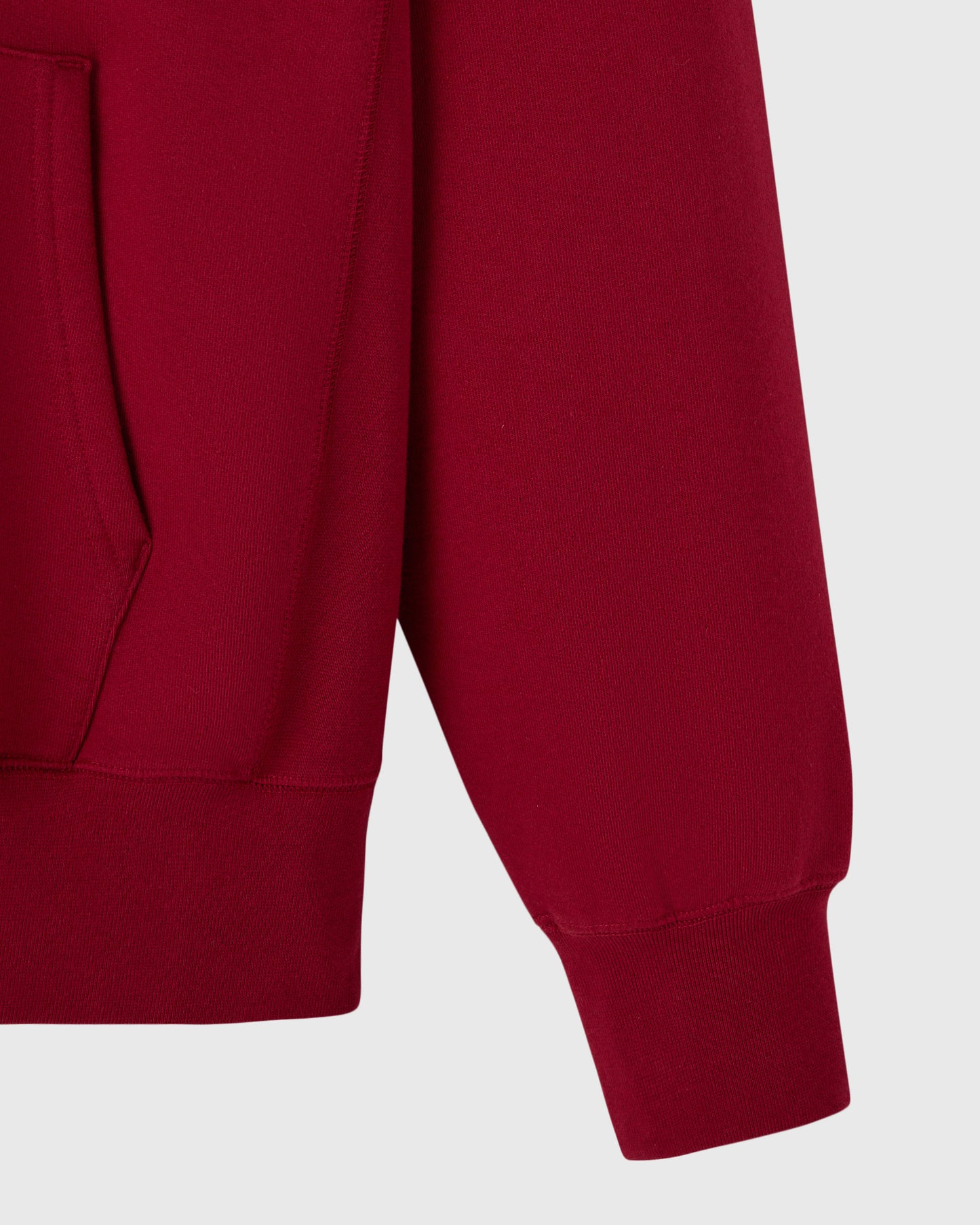 Deep red hoodie with ribbed cuffs and kangaroo pocket visible on left side.