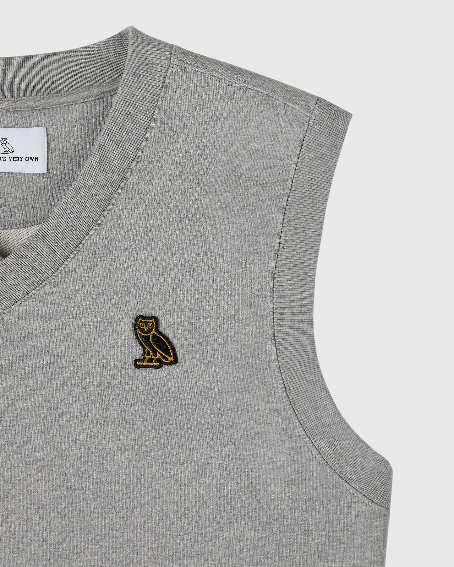 Heather grey sleeveless vest with ribbed neckline and armholes, featuring small gold owl embroidery on chest.