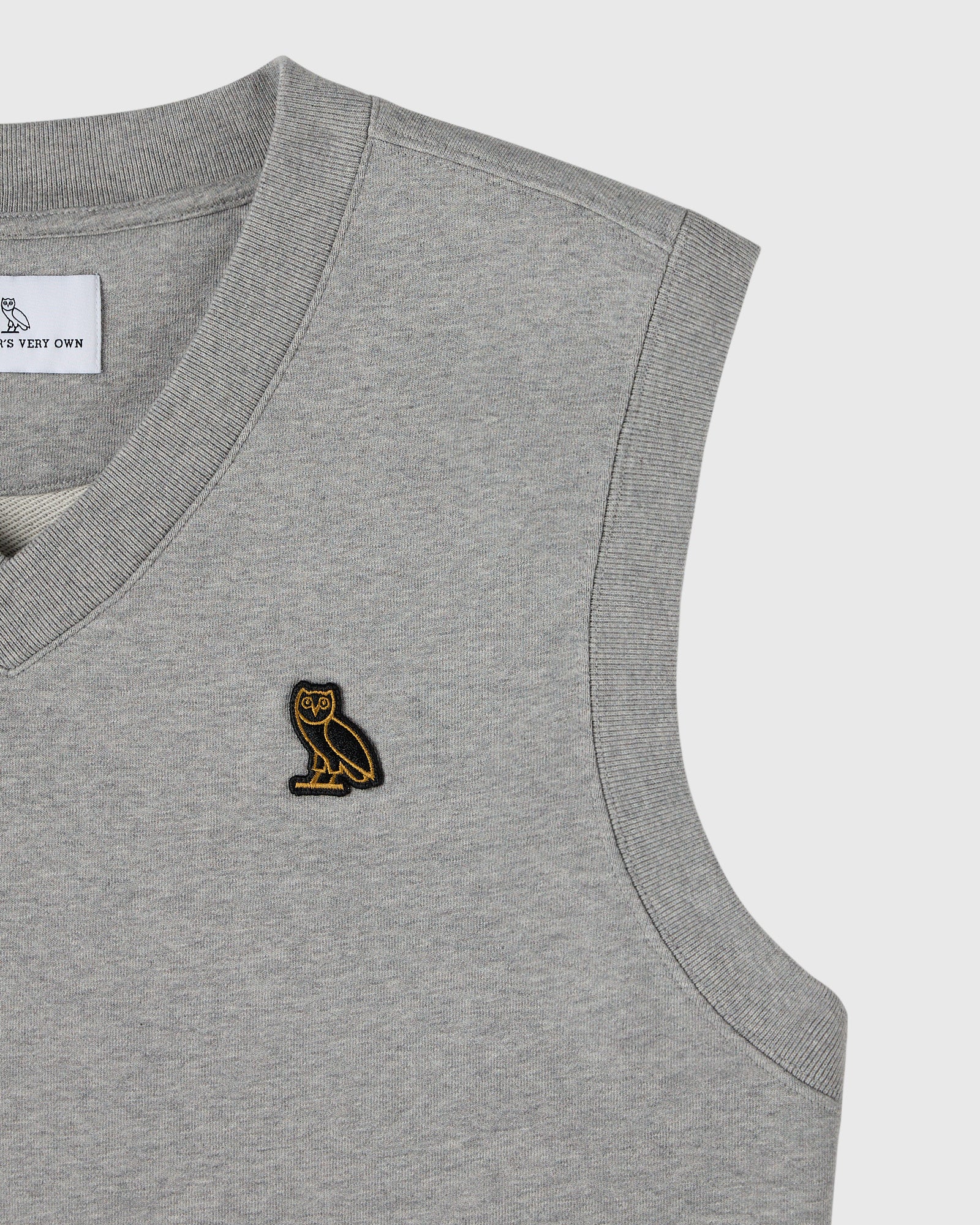 Heather grey sleeveless vest with ribbed neckline and armholes, featuring small gold owl embroidery on chest.