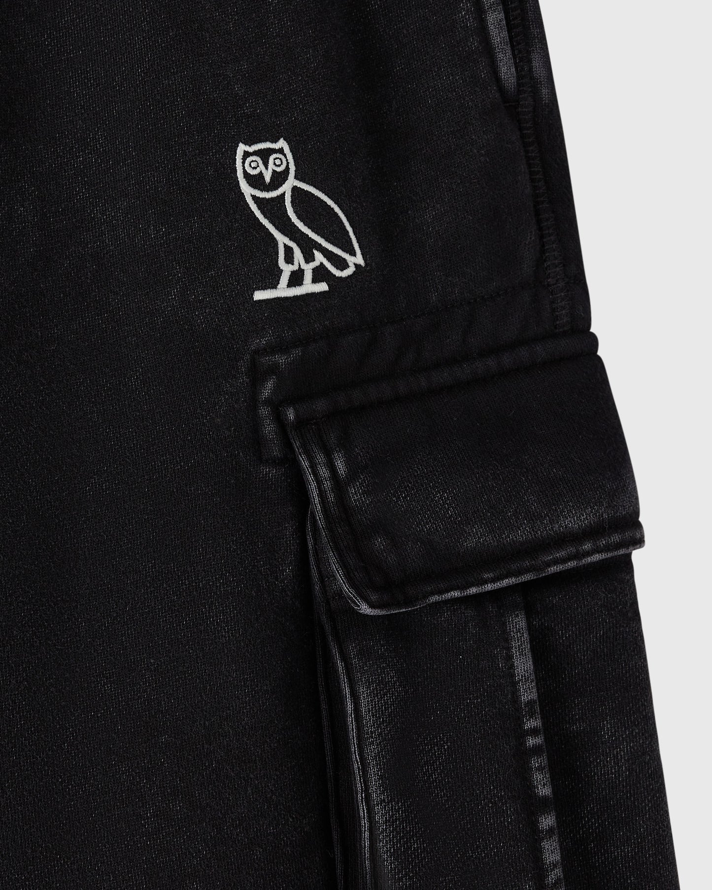 Black cargo sweatpant with white owl embroidery on chest and flap pocket on thigh.