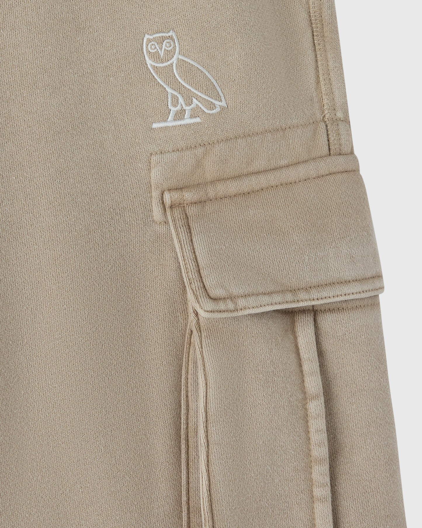 Sandstone cargo sweatpant with white owl embroidery on thigh and cargo pocket detail.