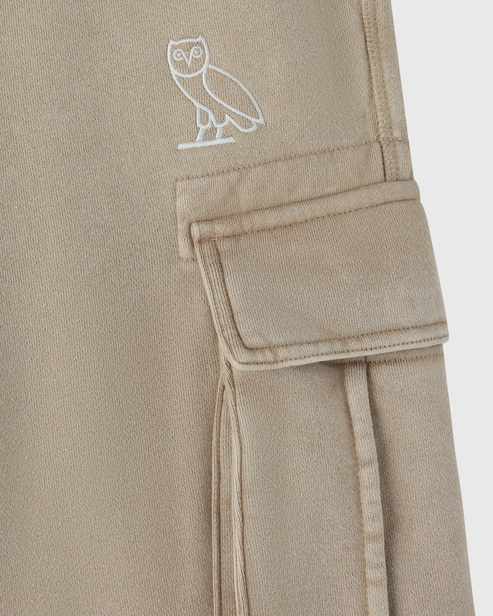 Sandstone cargo sweatpant with white owl embroidery on thigh and cargo pocket detail.