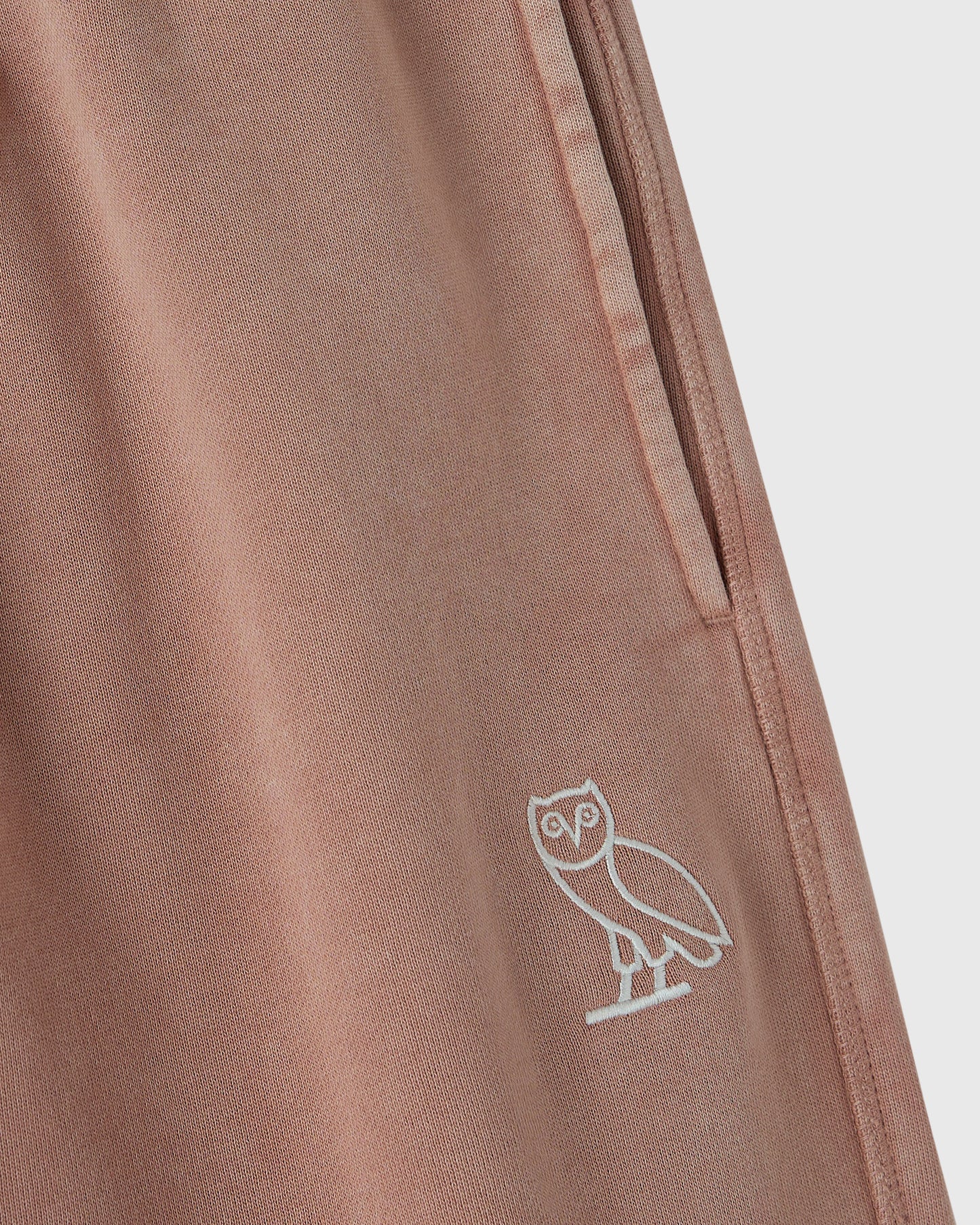Clay pink sweatpant with white owl embroidery on leg and side seam detail.