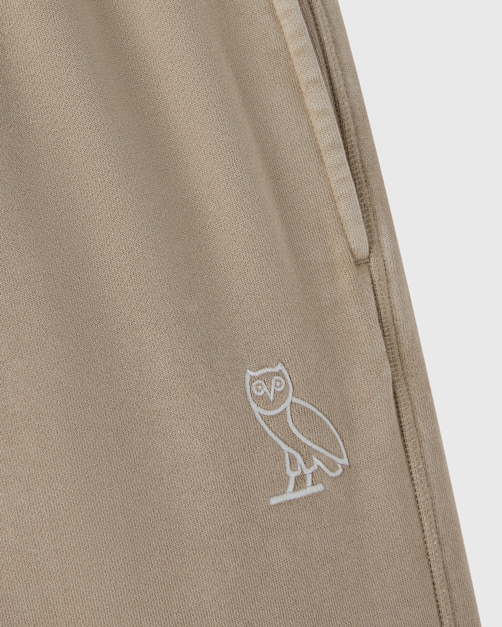 Sandstone sweatpant with white owl embroidery on the leg and side seam detail.