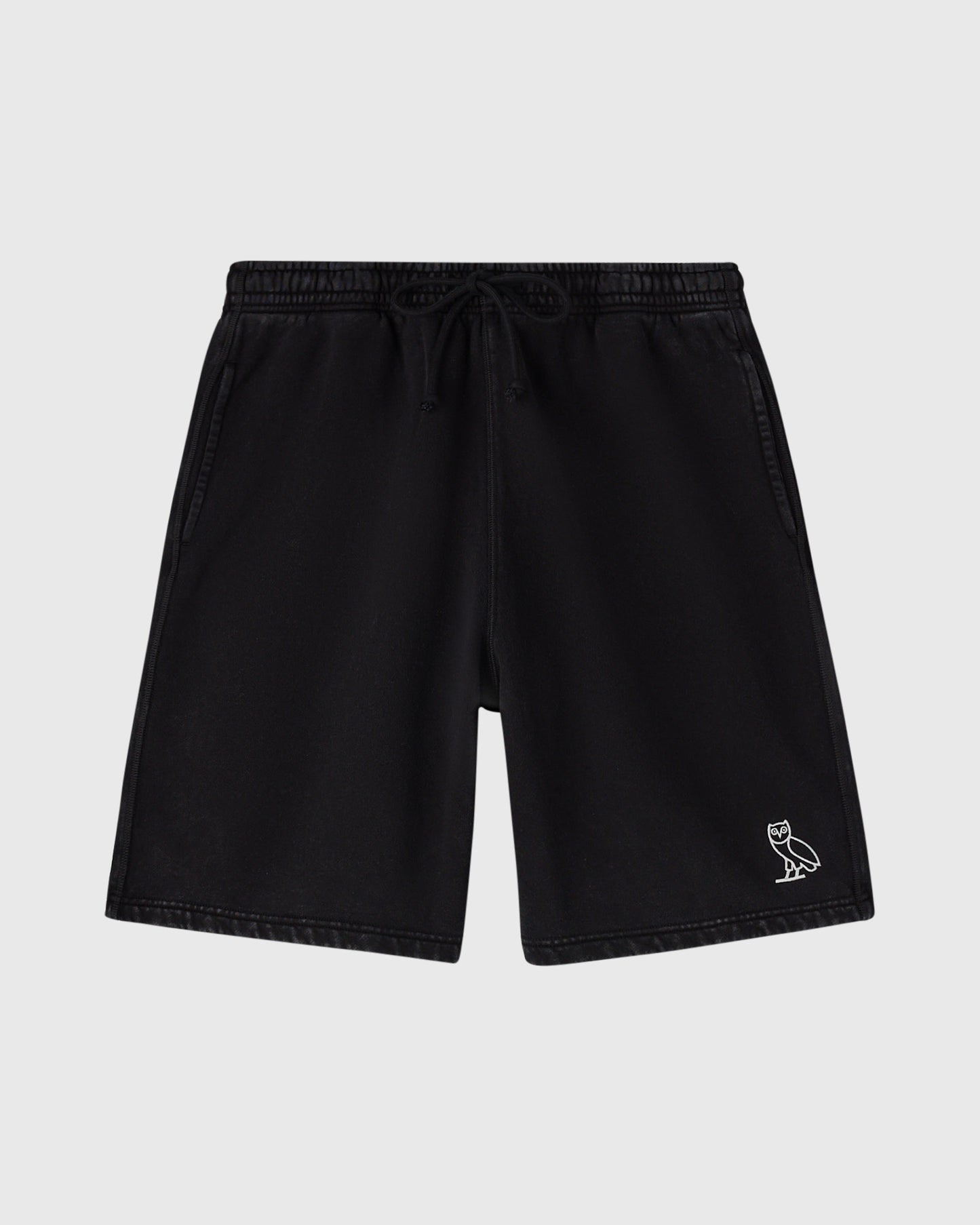 Black sweatshorts with drawstring waist, side pockets, and small owl emblem on right leg.