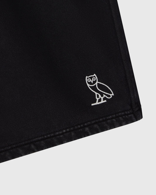 Black sweatshorts with white owl embroidery on the leg and stitched hem detail.