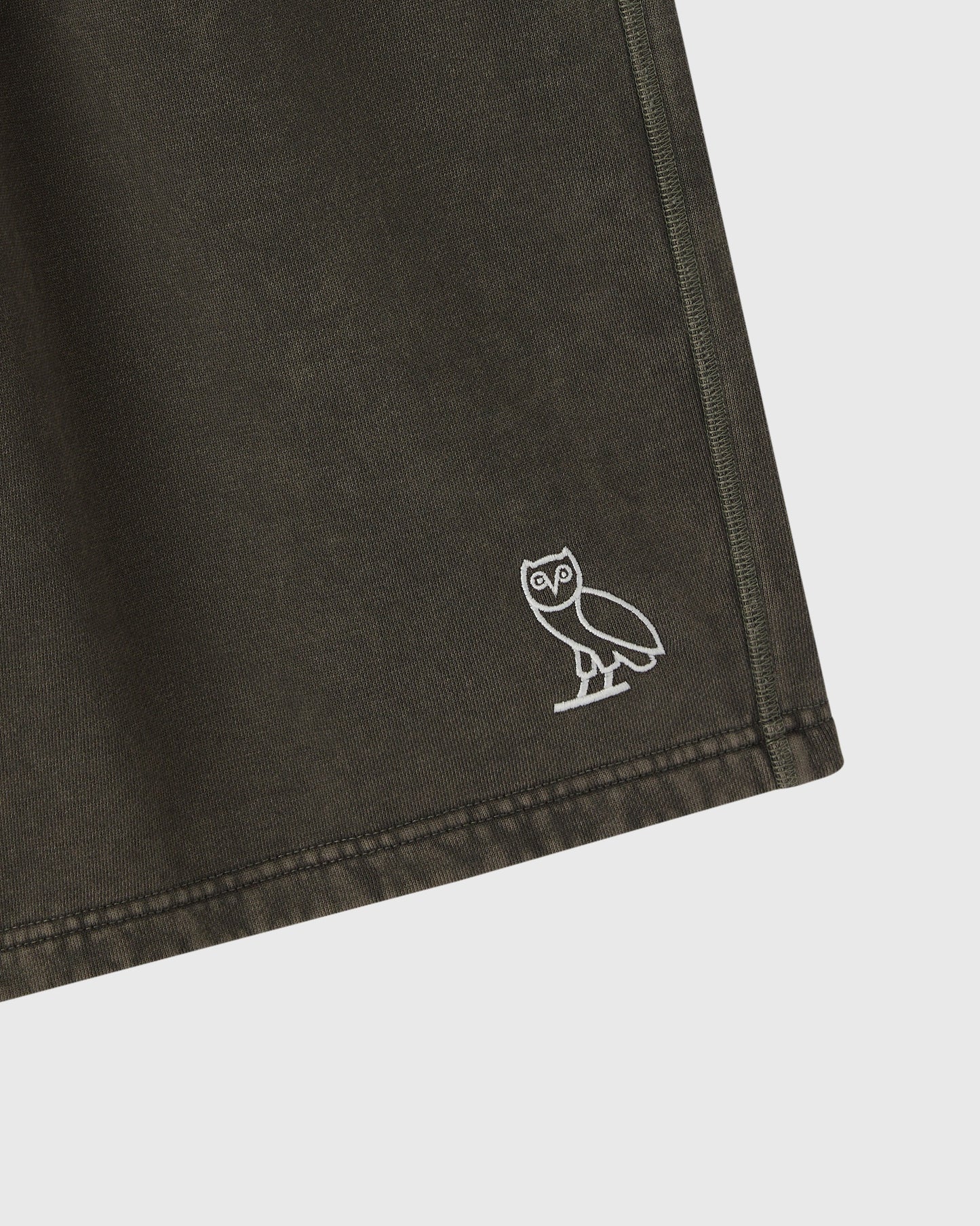 Deep olive sweatshorts with white owl logo embroidered on thigh.
