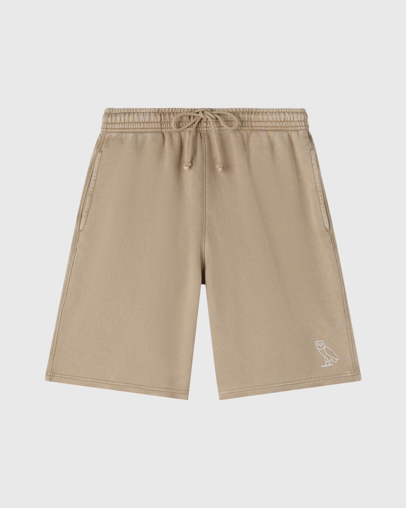 Beige sweatshorts with drawstring waist, side pockets, and small owl embroidery on lower right leg.
