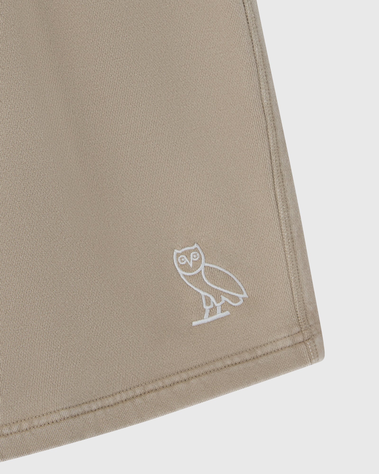 Sandstone sweatshorts with white embroidered owl logo on leg.
