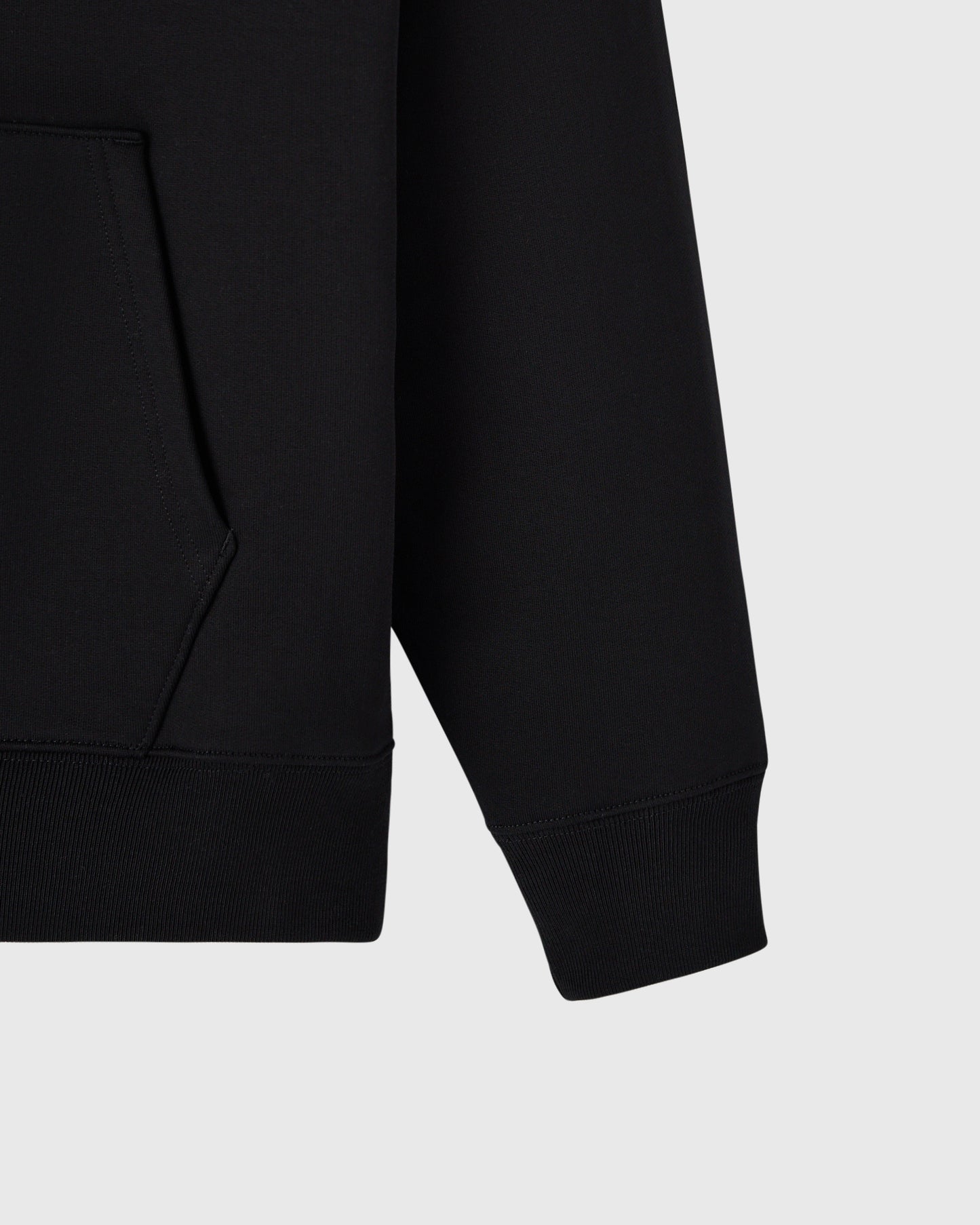 Black hoodie with ribbed cuffs and kangaroo pocket visible on left side.
