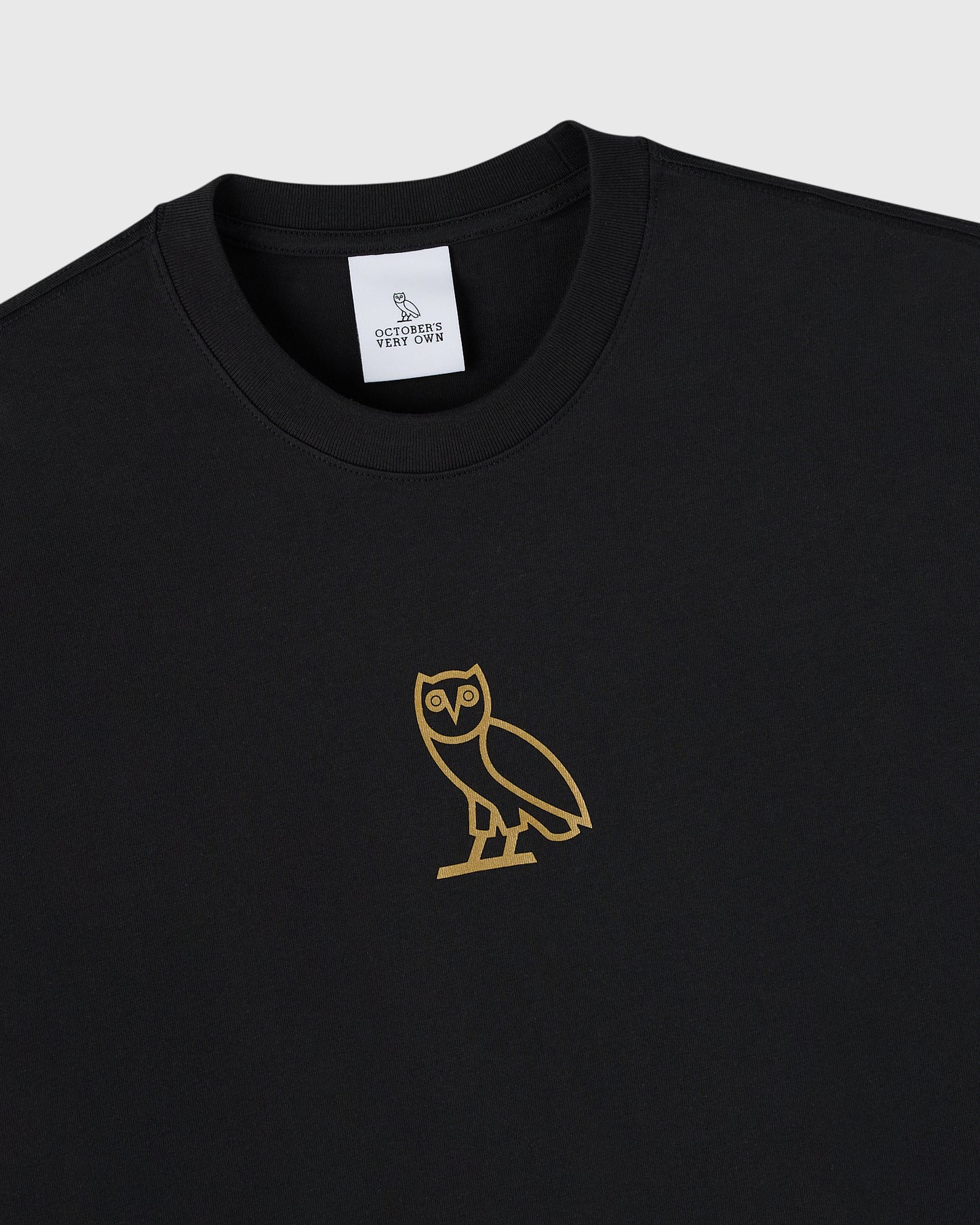 Black crewneck t-shirt with gold owl graphic on chest and brand label on neckline.