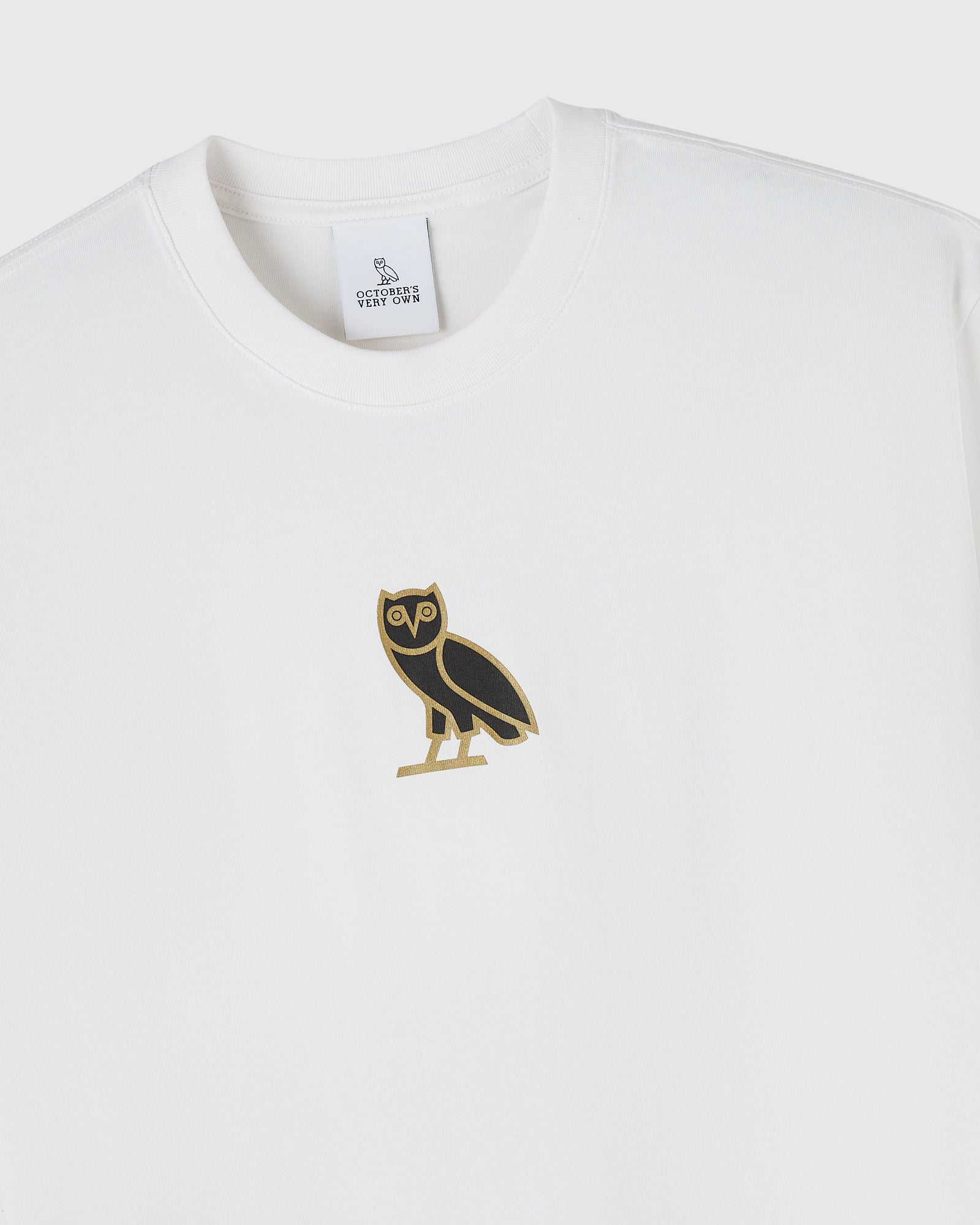 White crewneck t-shirt with black and gold owl graphic on chest and brand label at neckline.
