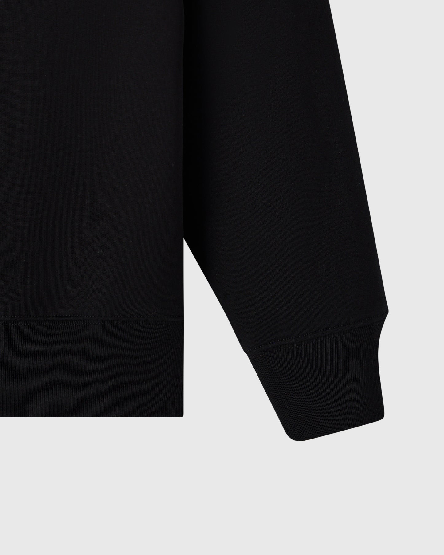 Black crewneck sweatshirt with ribbed cuffs and hem shown from the side.