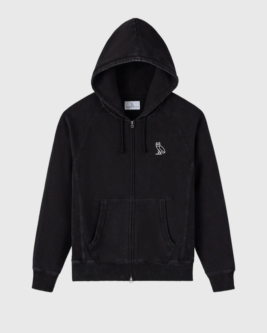 Black garment-dyed raglan hoodie with full-length zip, drawstring hood, and small owl emblem on chest.