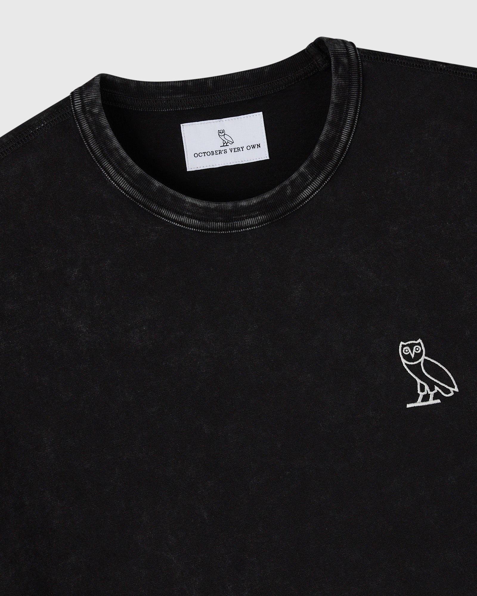 Black crewneck t-shirt with white owl embroidery on chest and brand label visible at neckline.