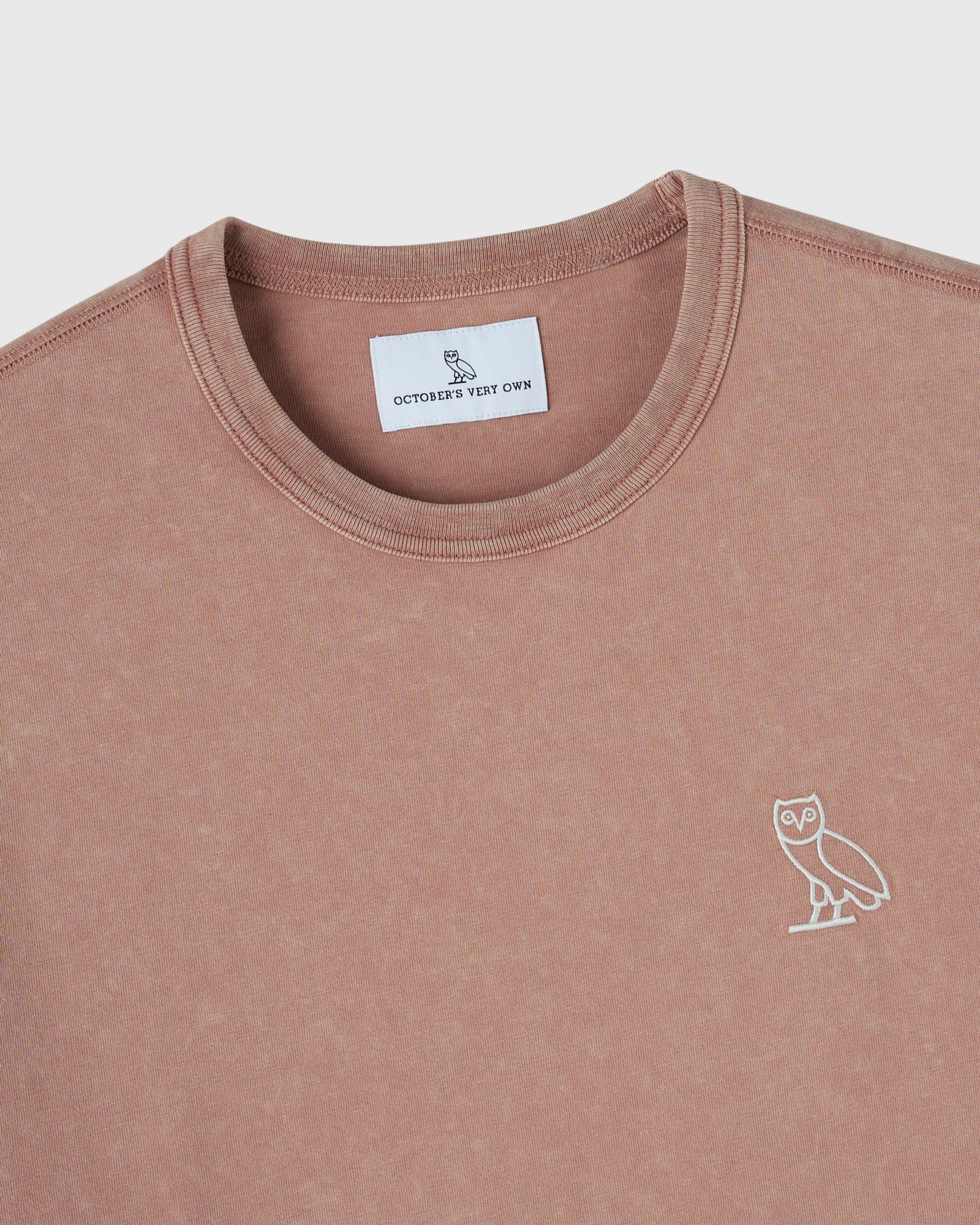 Clay pink crewneck t-shirt with small owl outline embroidered on chest and brand label at neckline.