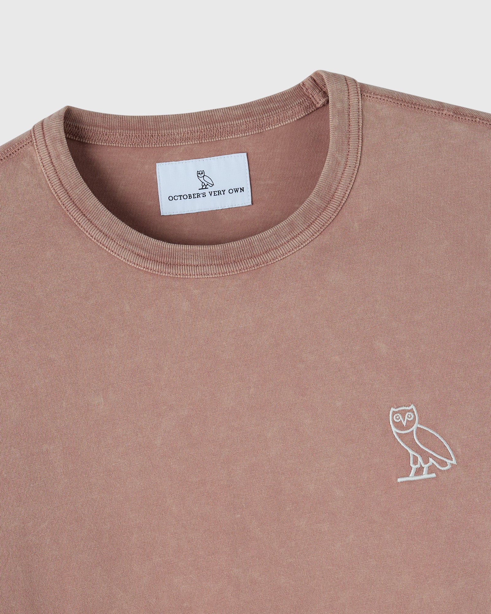 Clay pink long-sleeve crewneck tee with white owl embroidery on chest and brand label visible at neckline.