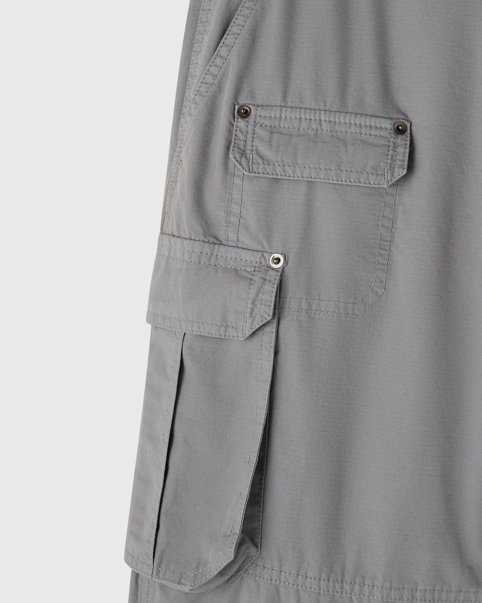 Grey cargo pants with multiple buttoned pockets on the thighs and side panels.