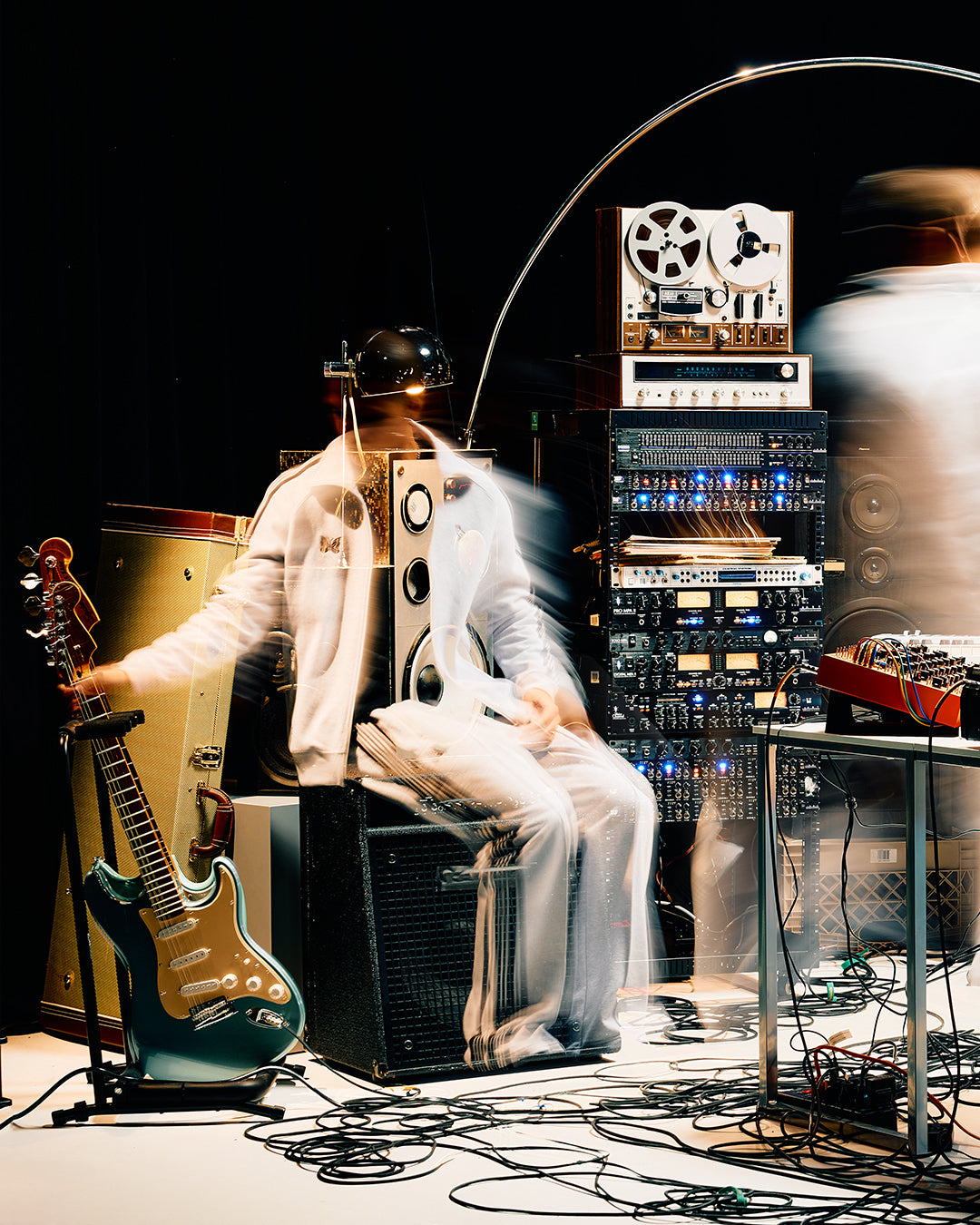 Person playing guitar with electronic equipment and cables in a dark setting