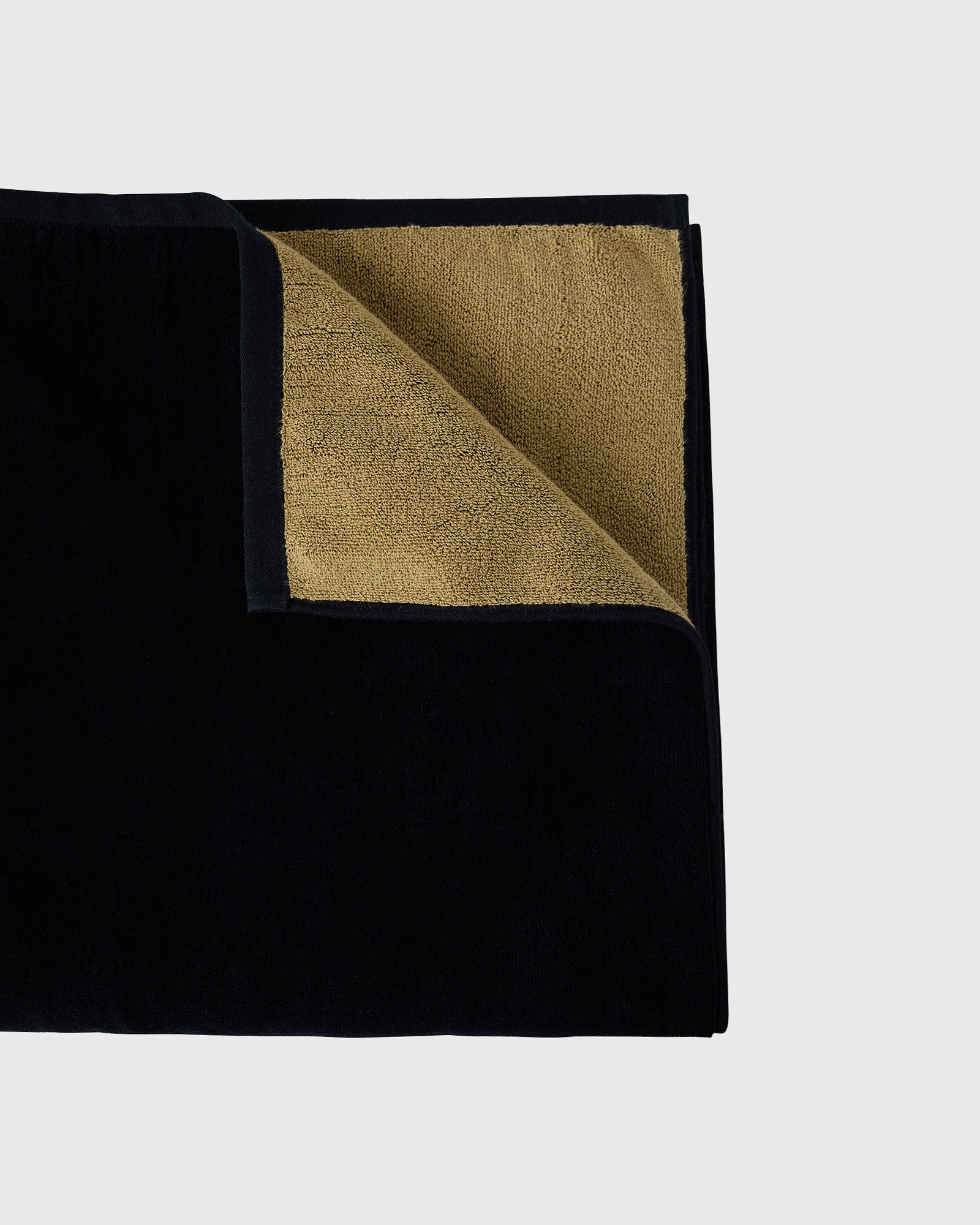 Black towel with gold-toned interior lining, folded corner detail visible.