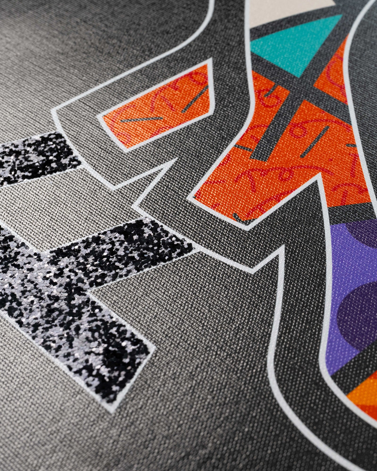 Colorful abstract print with geometric shapes in orange, turquoise, purple, and black sequins on gray fabric background.