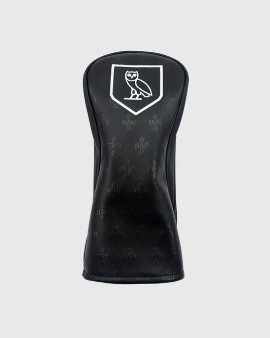 Black golf driver headcover with white owl logo in shield on front and repeating monogram pattern.
