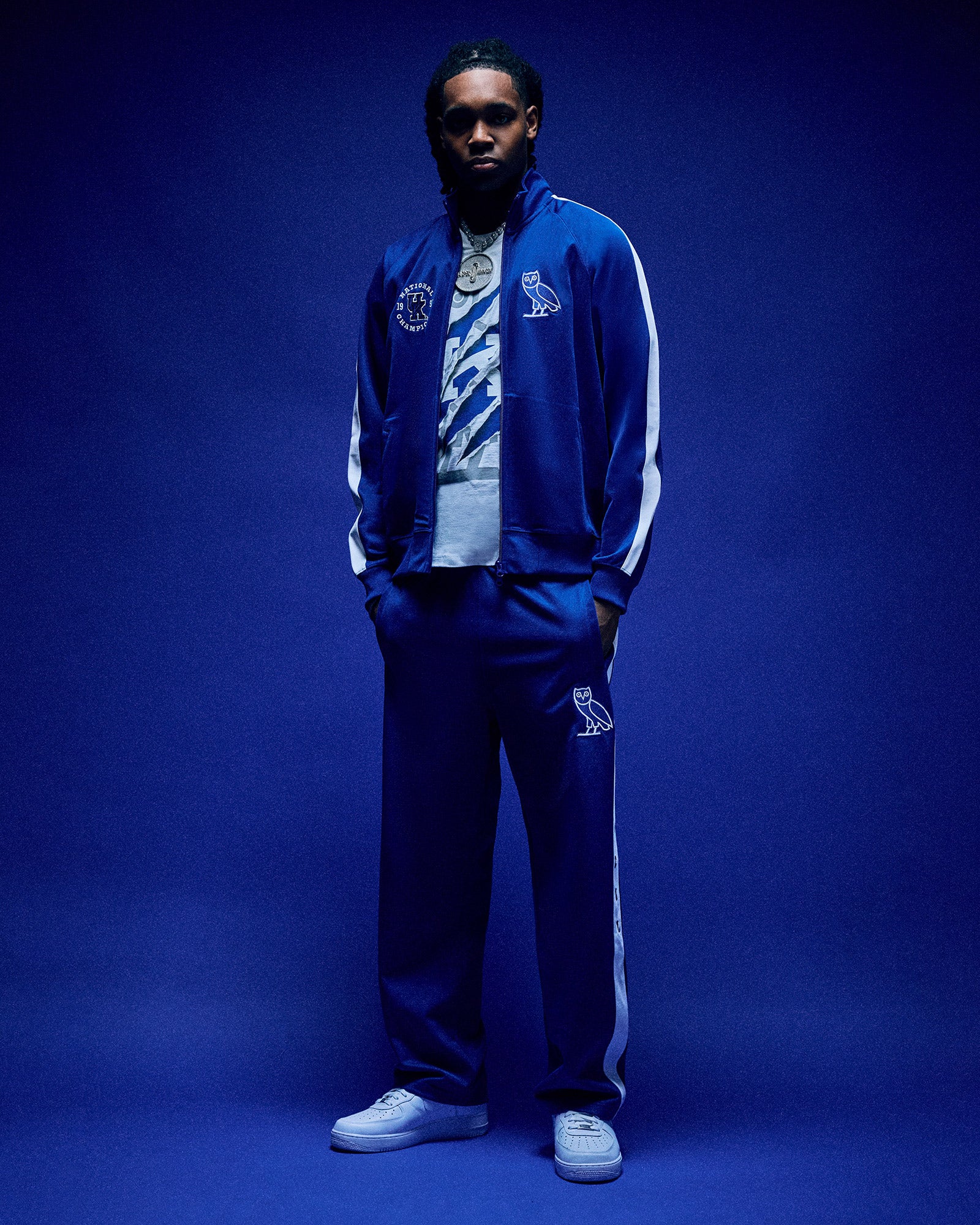 Person wearing a blue October's Very Own x Kentucky Wildcats tracksuit with white accents against a blue background