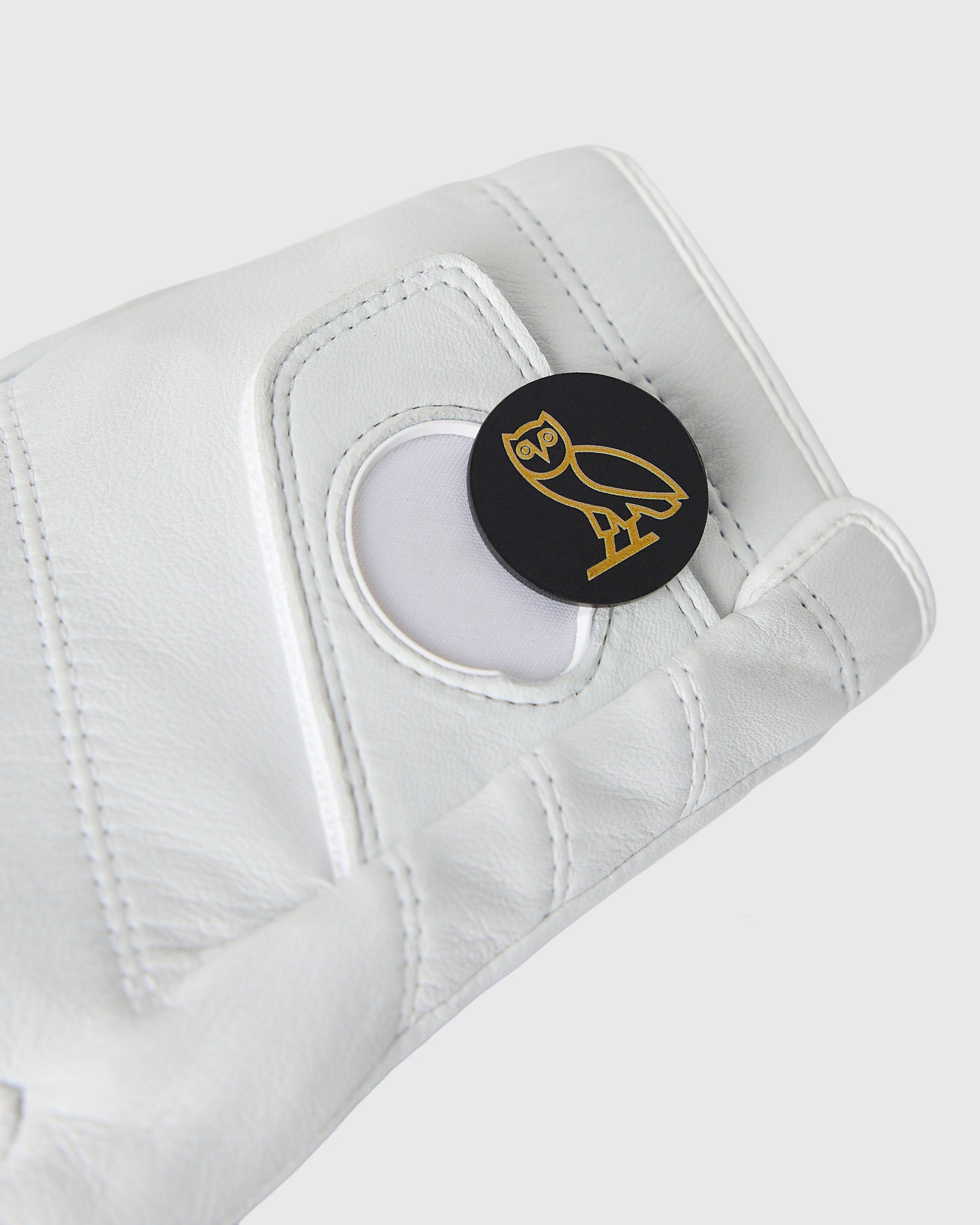 White leather left golf glove with Callaway owl logo ball marker on palm.