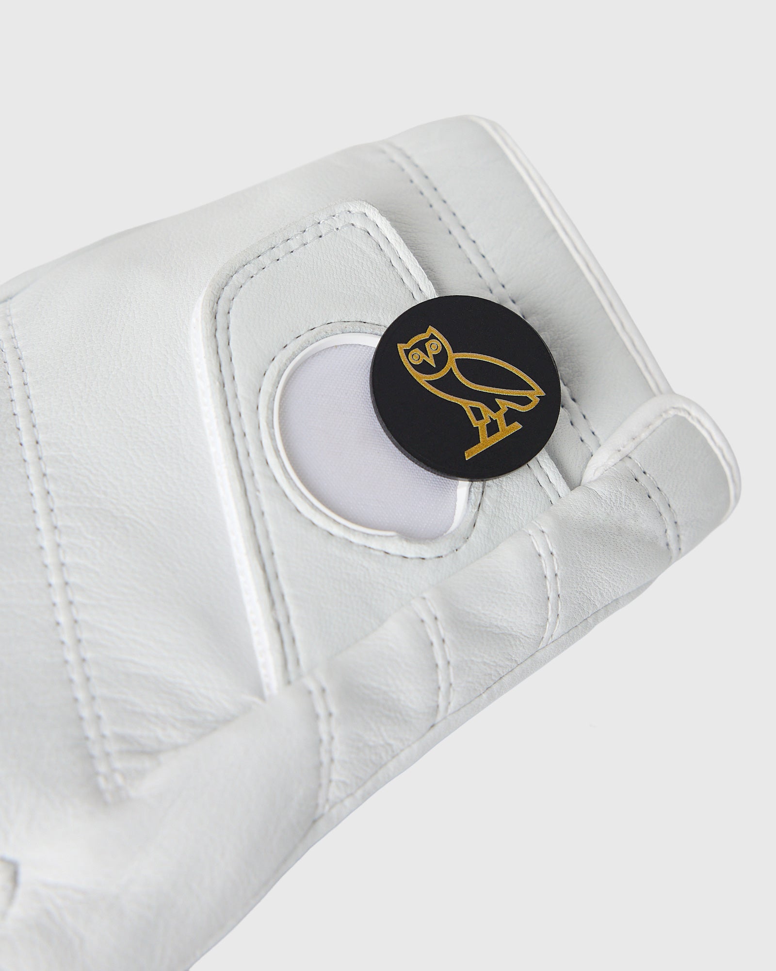 White leather left golf glove with Callaway owl logo ball marker on palm.