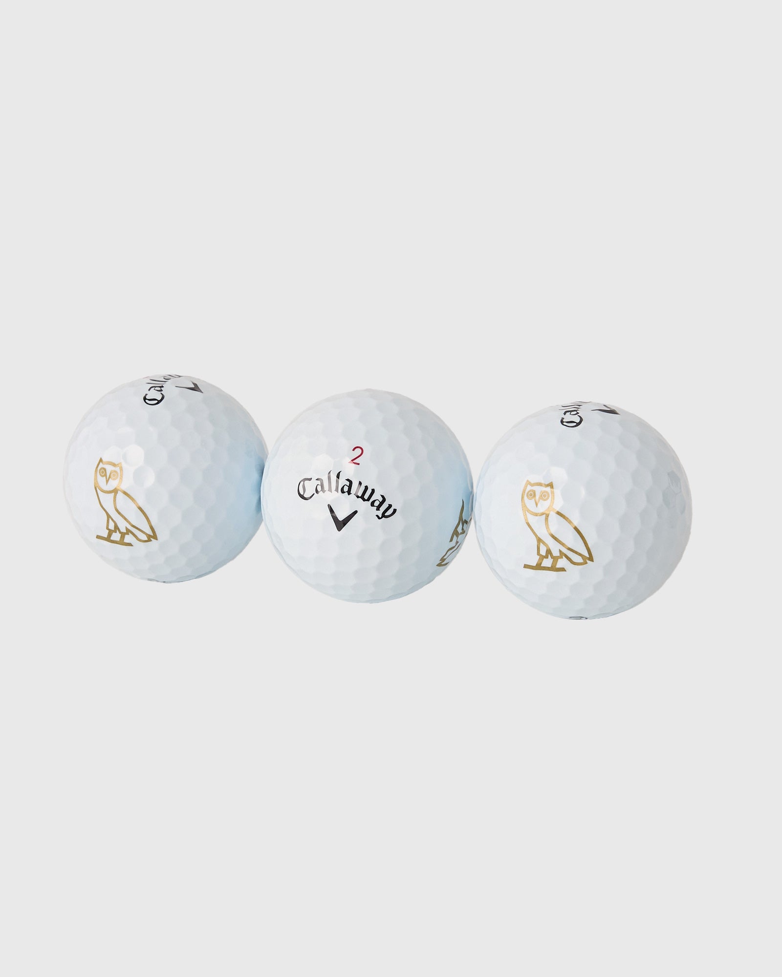 Three white Callaway Chrome Tour golf balls with dimple pattern, displaying triple diamond marking and gold owl logo.