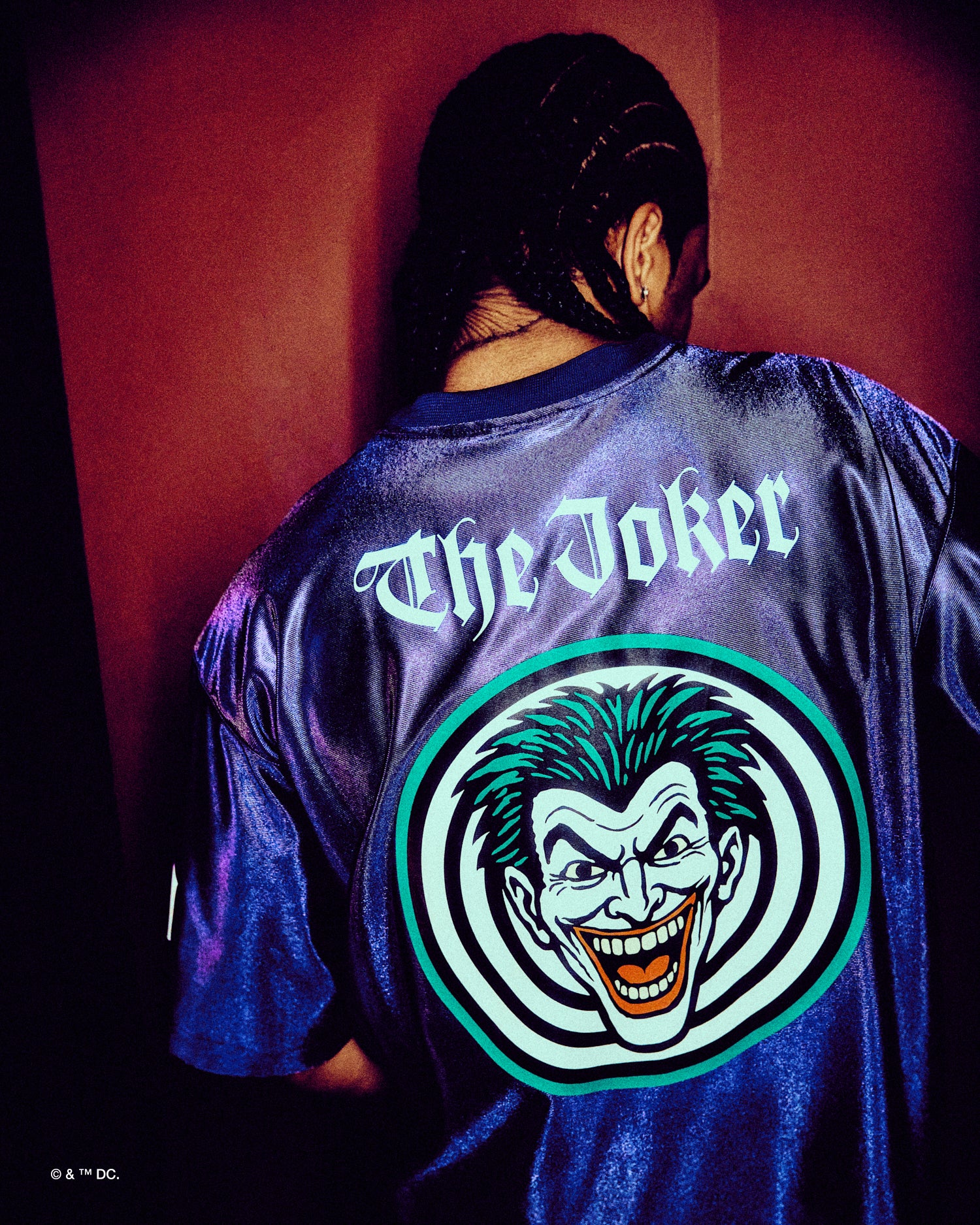Person wearing a Octpber's Very Own x Batman x The Joker 'The Joker' themed shirt with a graphic design on the back.