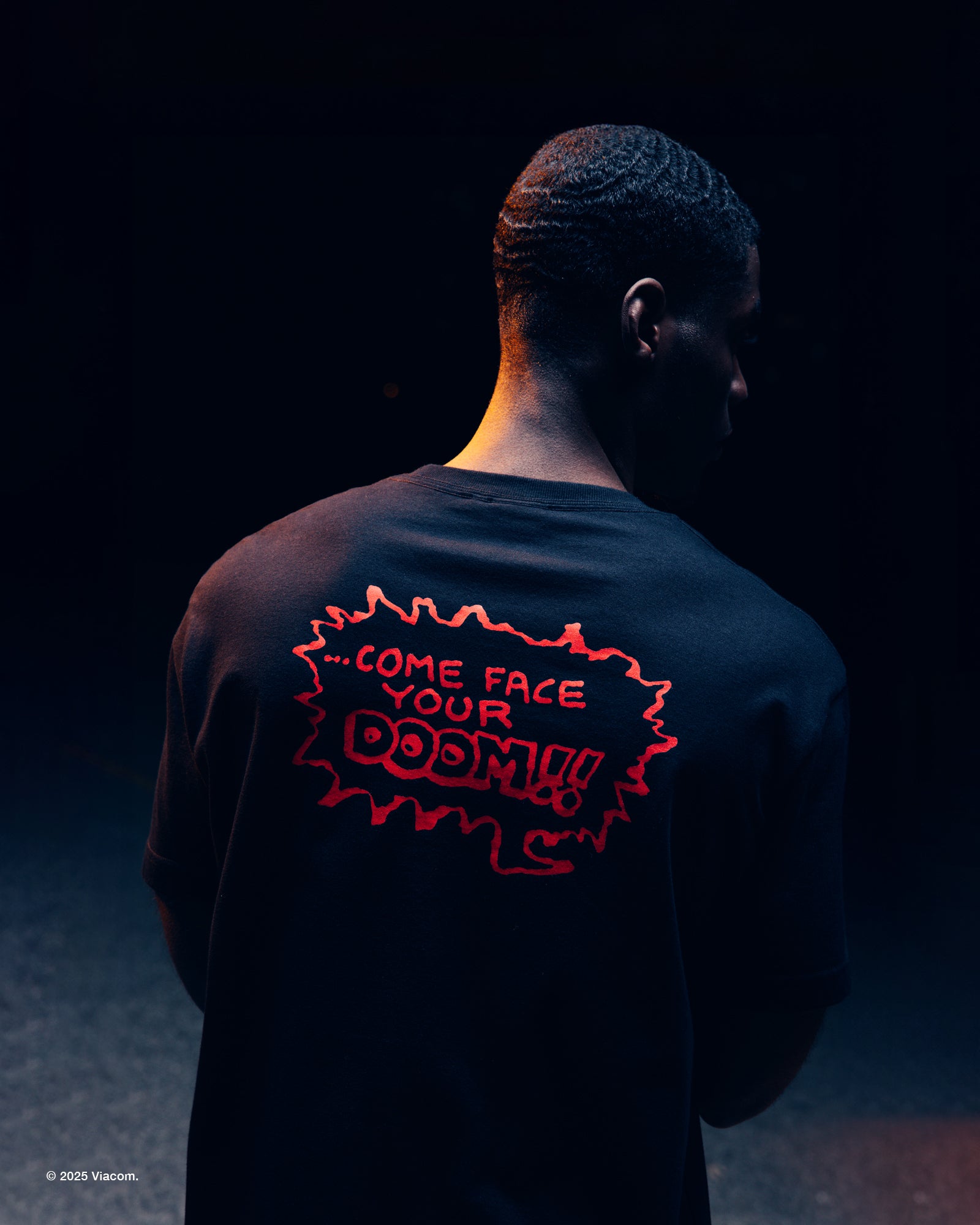 Person wearing a dark October's Very Own x TMNT shirt with red text on the back against a black background