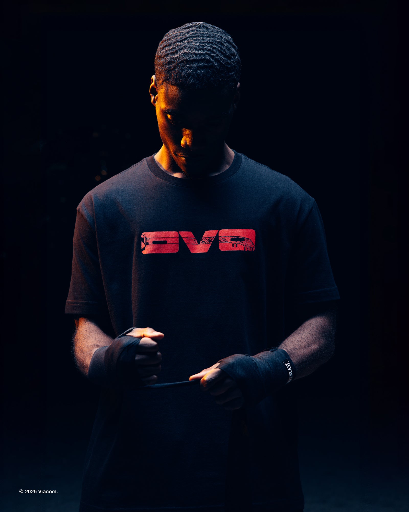 Person wearing a black October's Very Own x TMNT t-shirt with a red logo on a dark background
