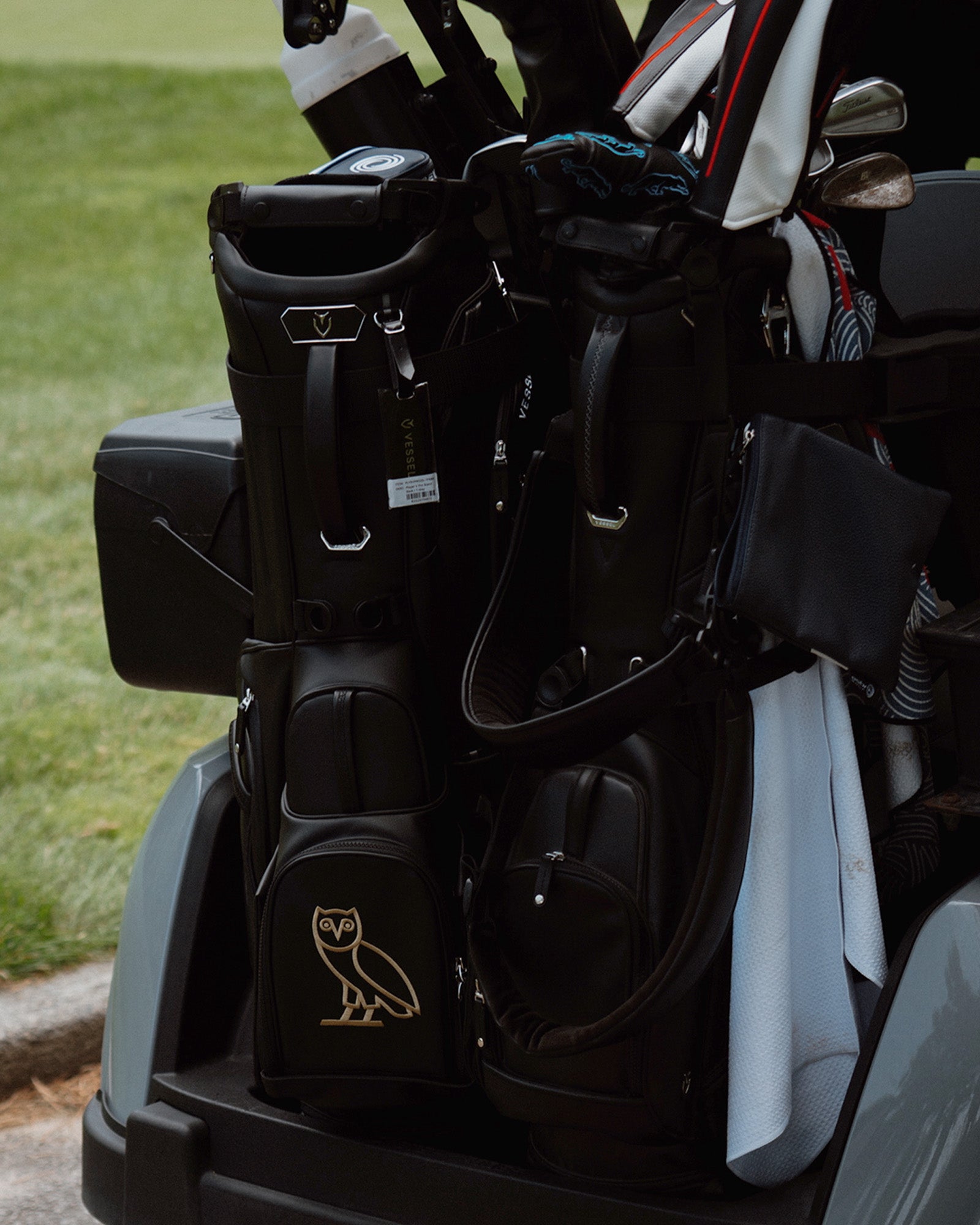 Golf bag with golf clubs and a visible October's Very Own logo on a golf course.