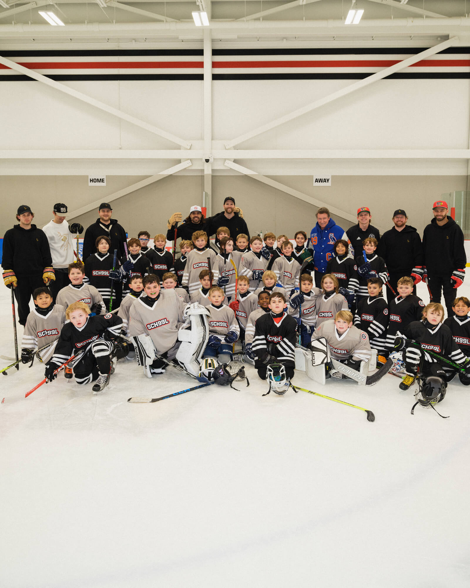 Group of young hockey players and coaches posing on an ice rink.