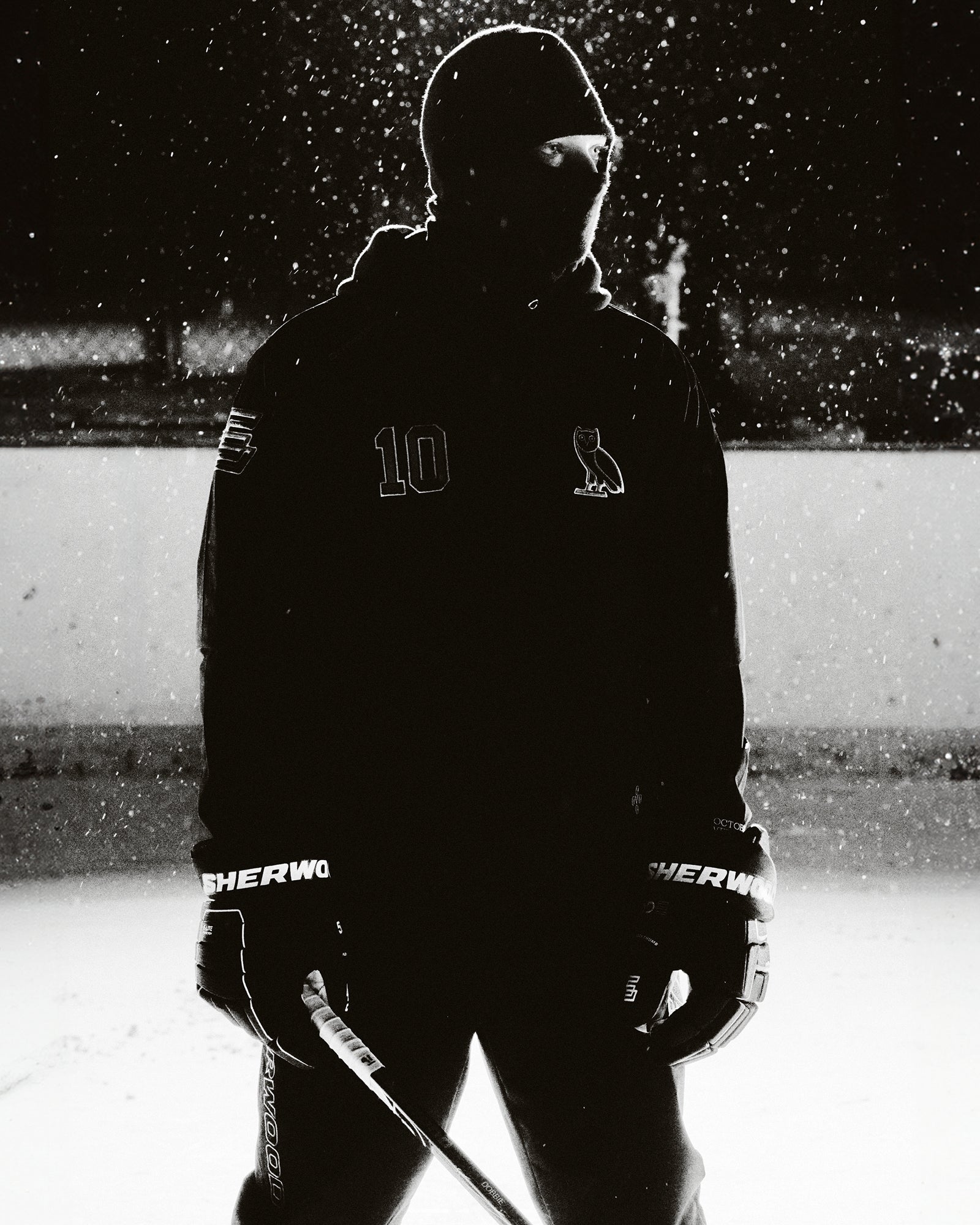 Person in October's Very Own hockey gear on an ice rink with snow falling
