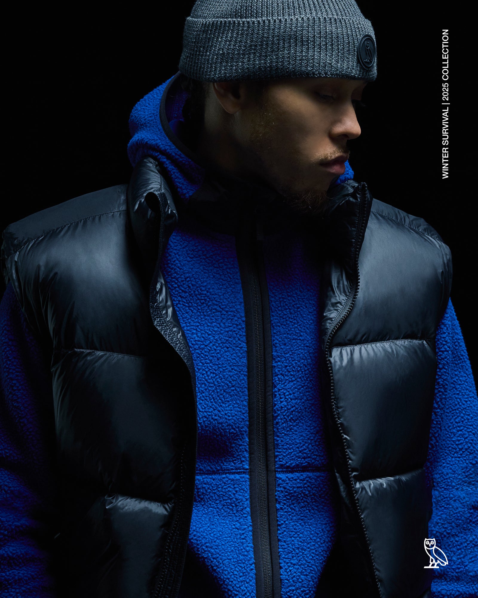 Person wearing a October's Very Own black puffer jacket and blue fleece with a dark background