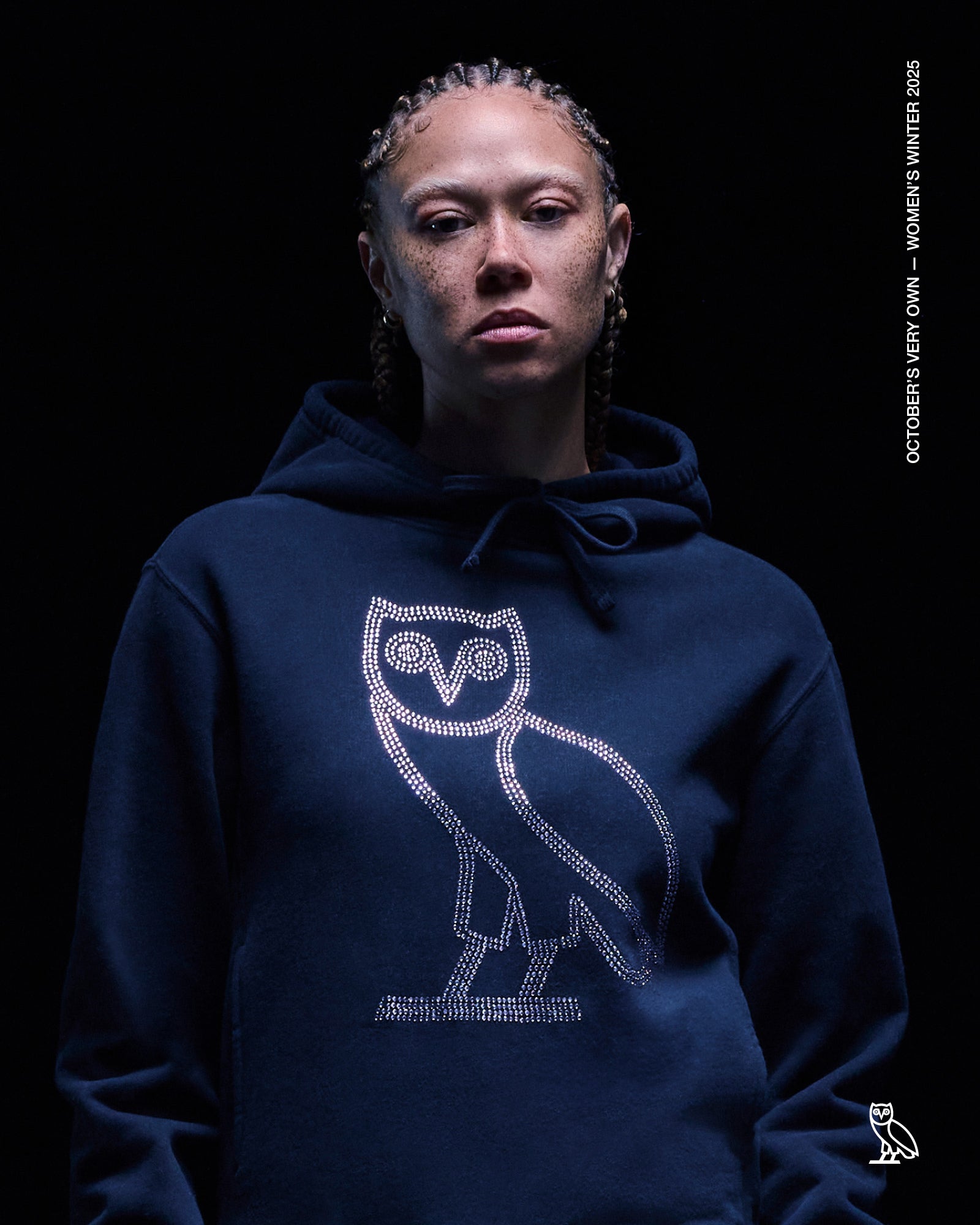 Person wearing a October's Very Own navy blue hoodie with an owl design on a black background